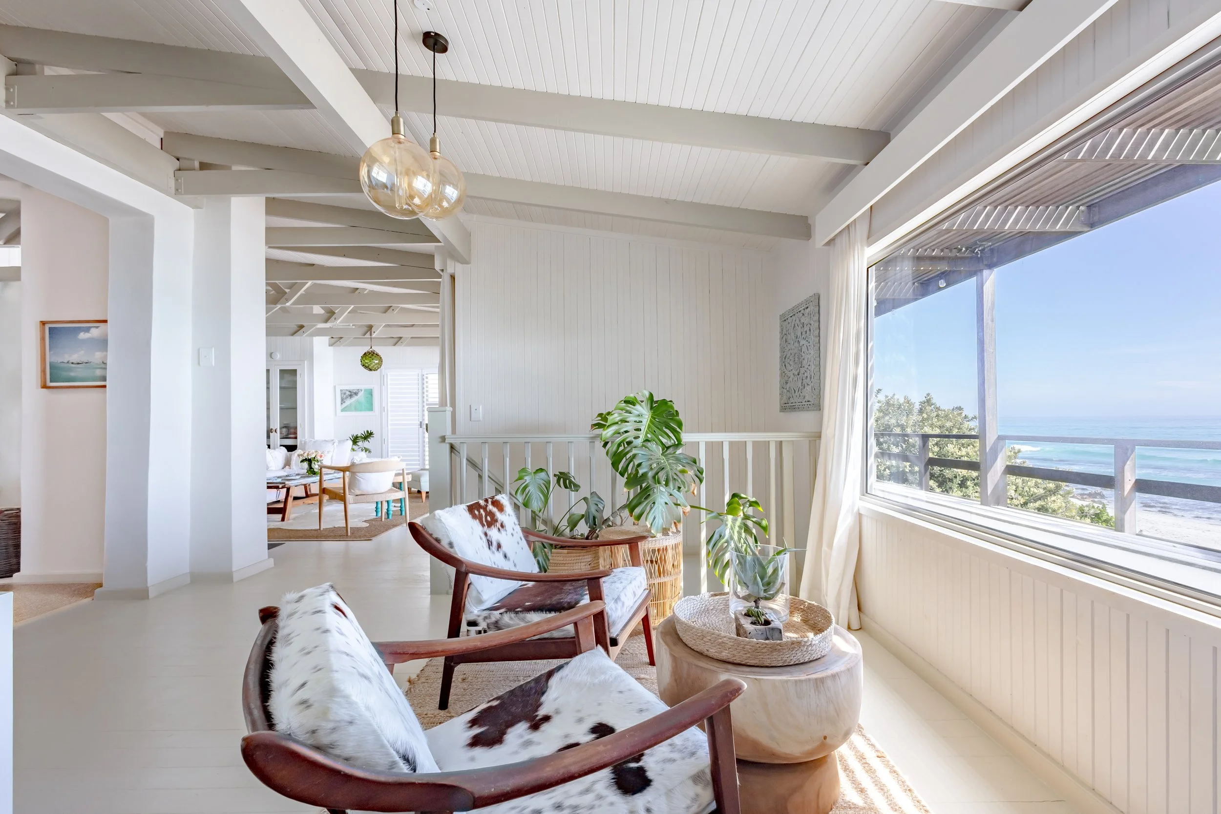 Cozy seating area with animal-print armchairs and a Monstera plant overlooking a window with a mountain view.