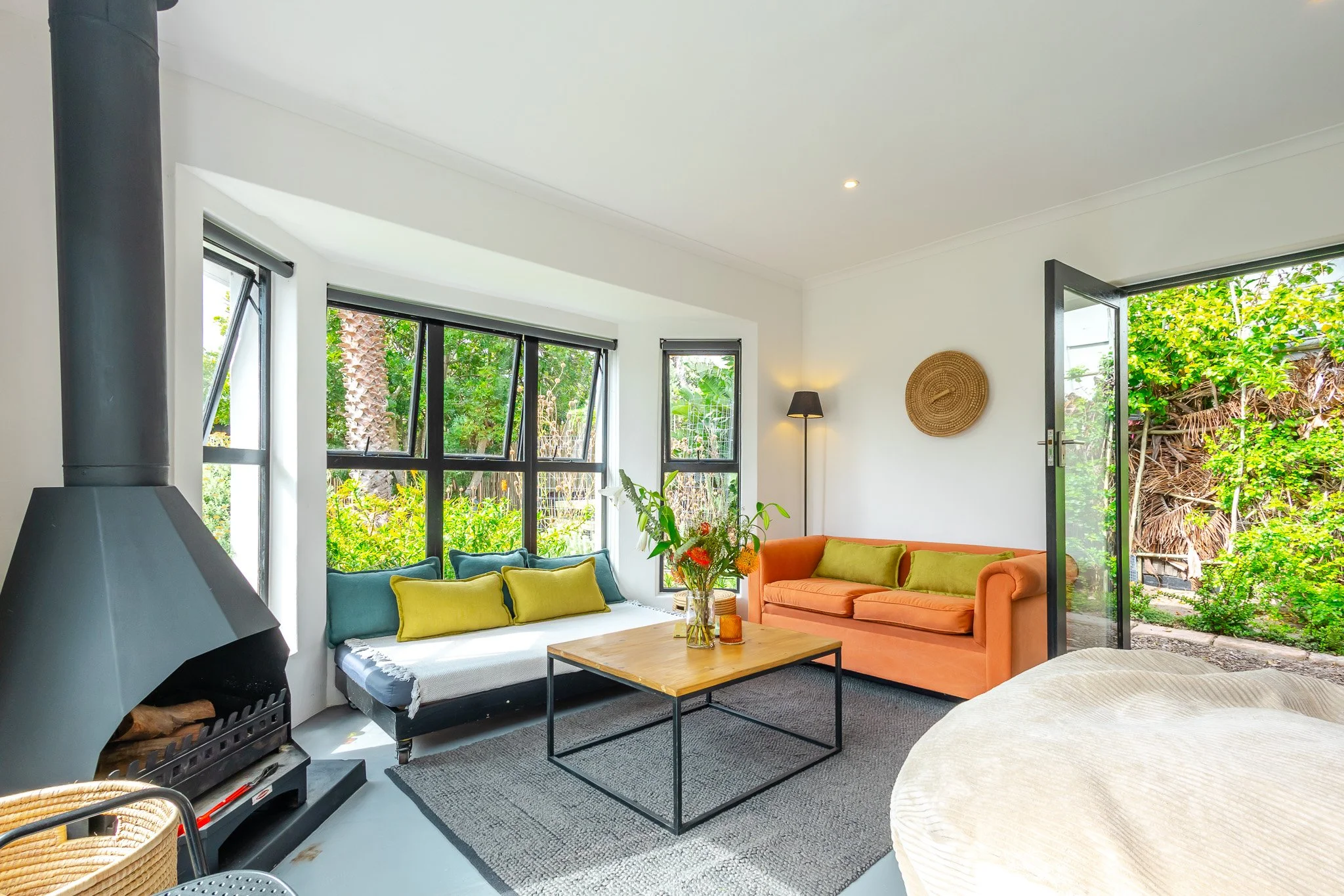 Wide-angle Airbnb photography of a colorful living area in Kommetjie, showcasing a modern orange sofa, wooden coffee table, and clean architectural lines.