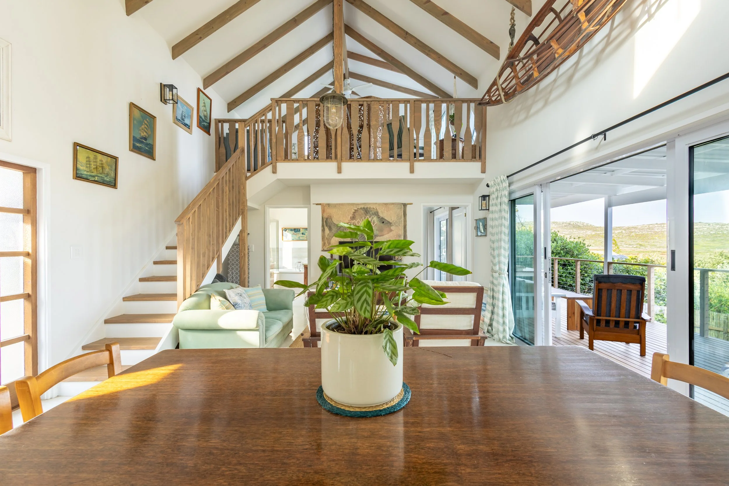 Spacious double-volume living room with mezzanine level photographed for a luxury holiday rental in Cape Town's Deep South.