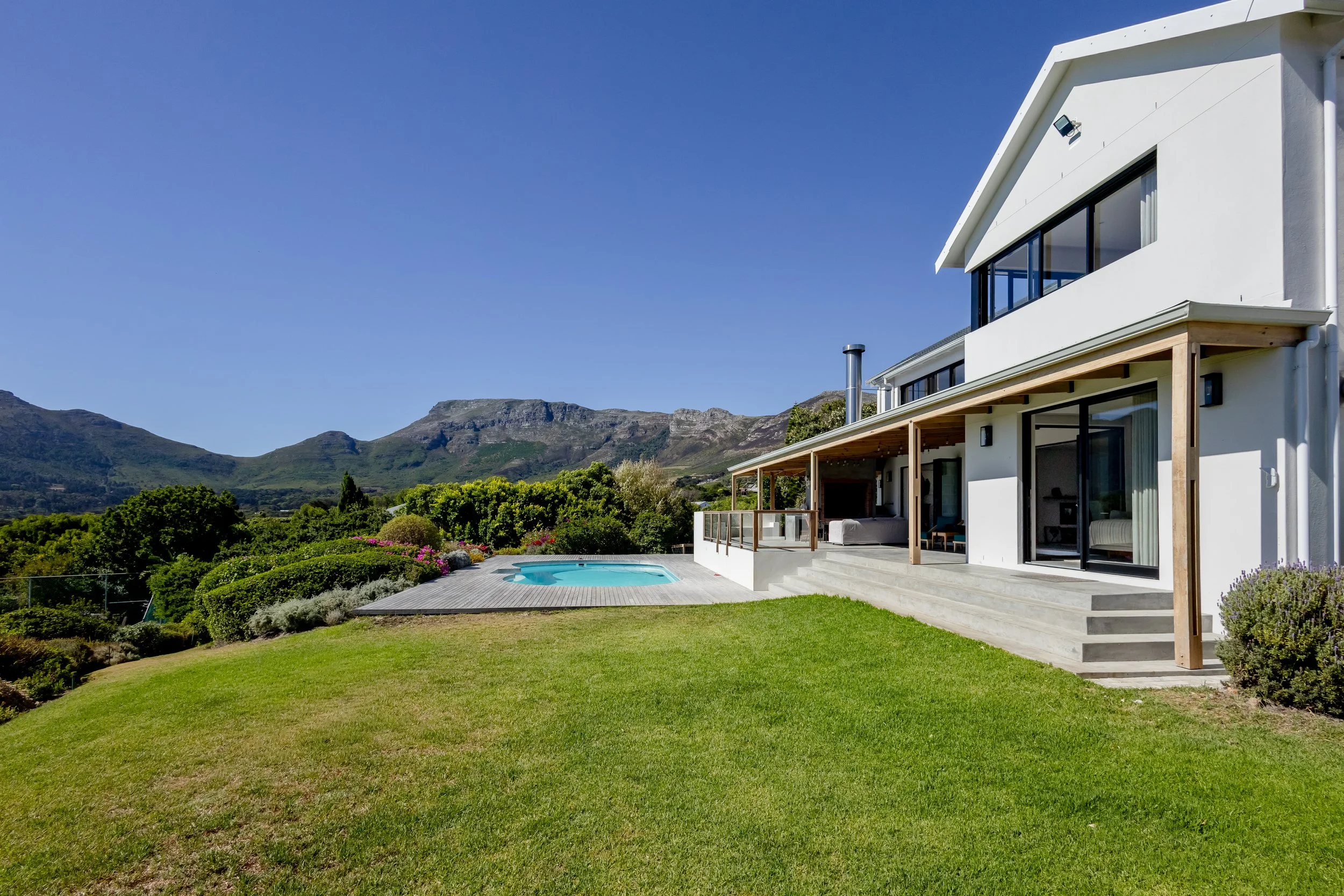 High-end property marketing image of a lush green lawn and pool deck at a luxury residence in Camps Bay.