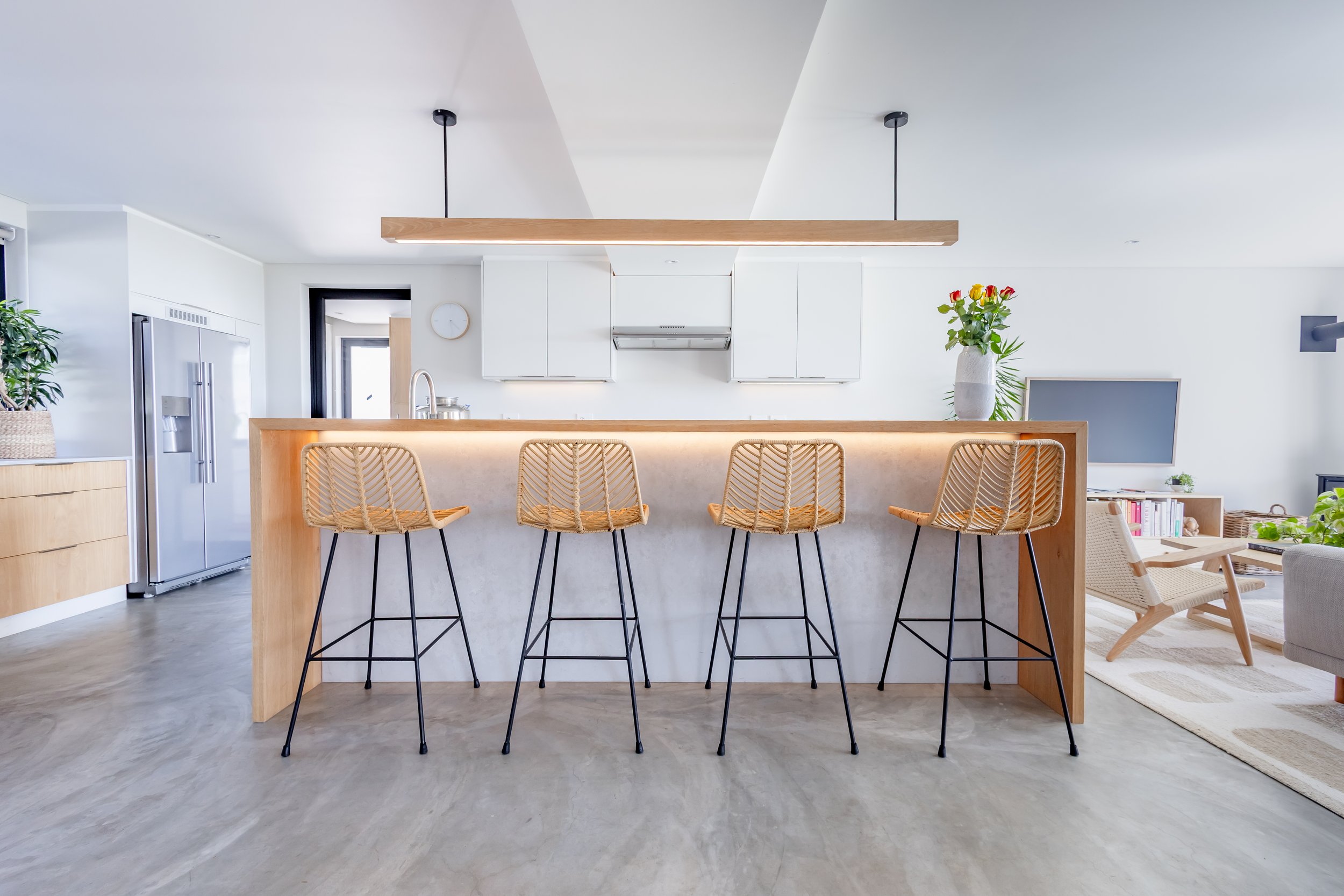 Modern Airbnb kitchen photography in Clifton featuring a sleek wooden breakfast bar, designer wicker stools, and minimalist pendant lighting.