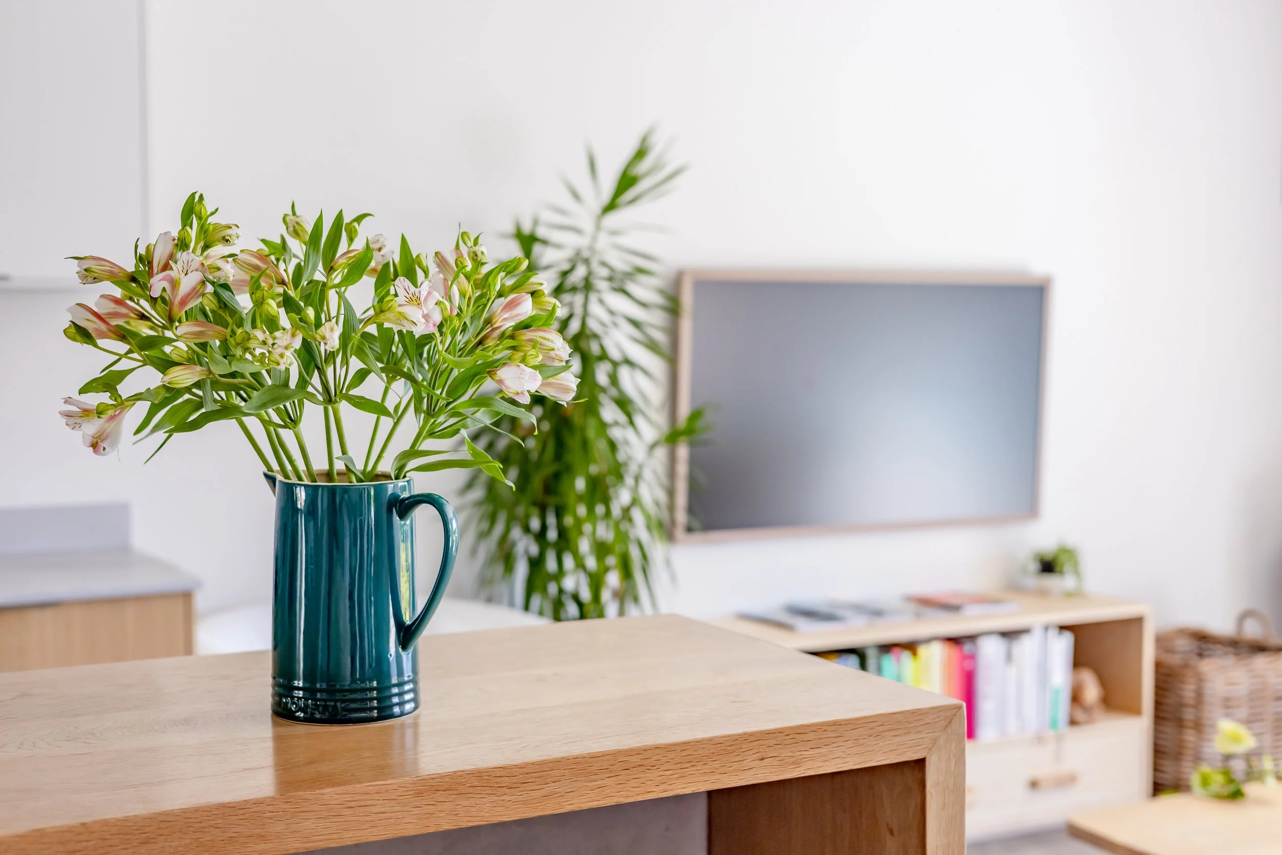 Interior lifestyle photography of a Cape Town seaboard property featuring fresh flowers on a wooden tabletop and soft-focus backgrounds.