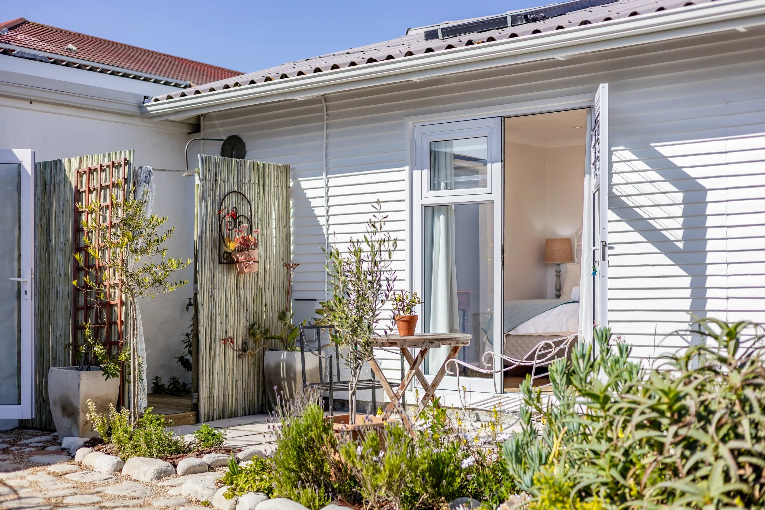 Charming exterior entrance to a coastal holiday home with landscaped garden, professionally photographed for Airbnb and property marketing in Cape Town.