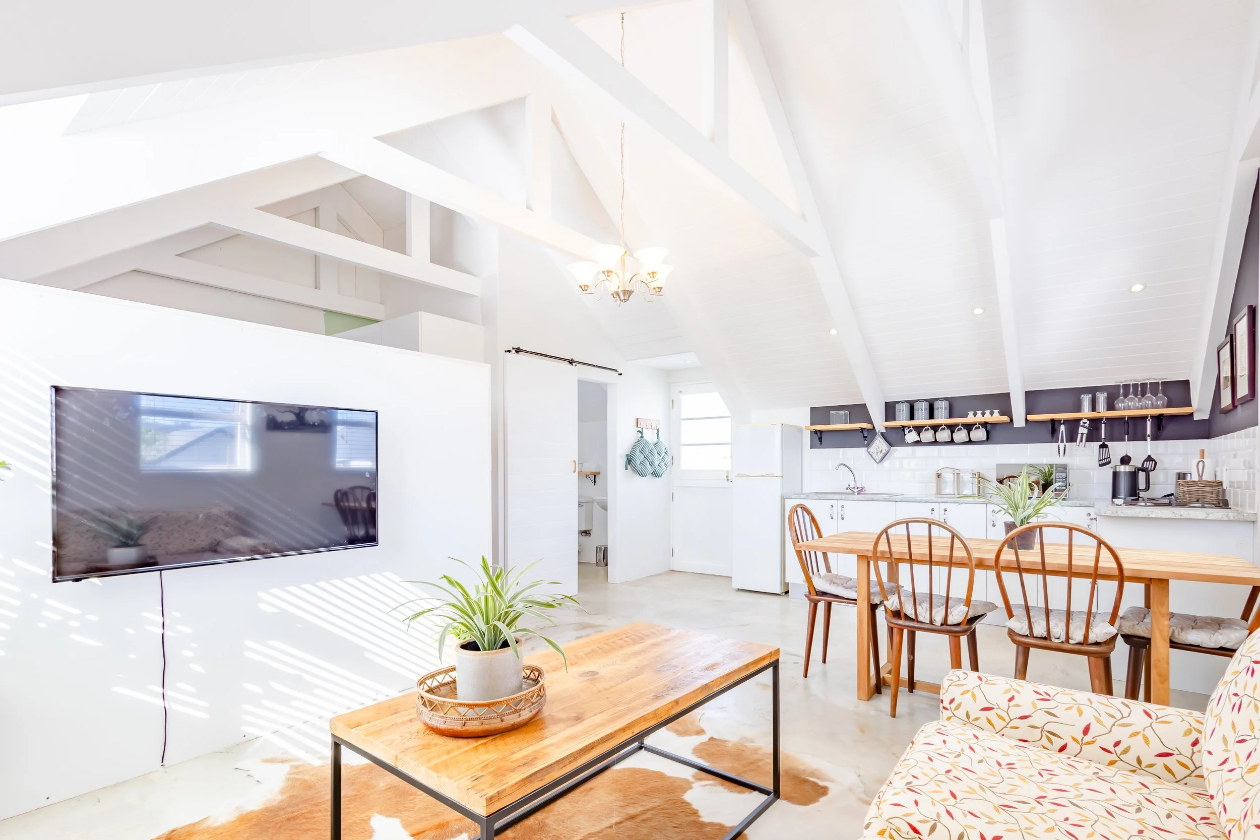 Wide-angle interior shot of a sun-lit Cape Town holiday rental, showing the seamless transition between the living space and the dining area.