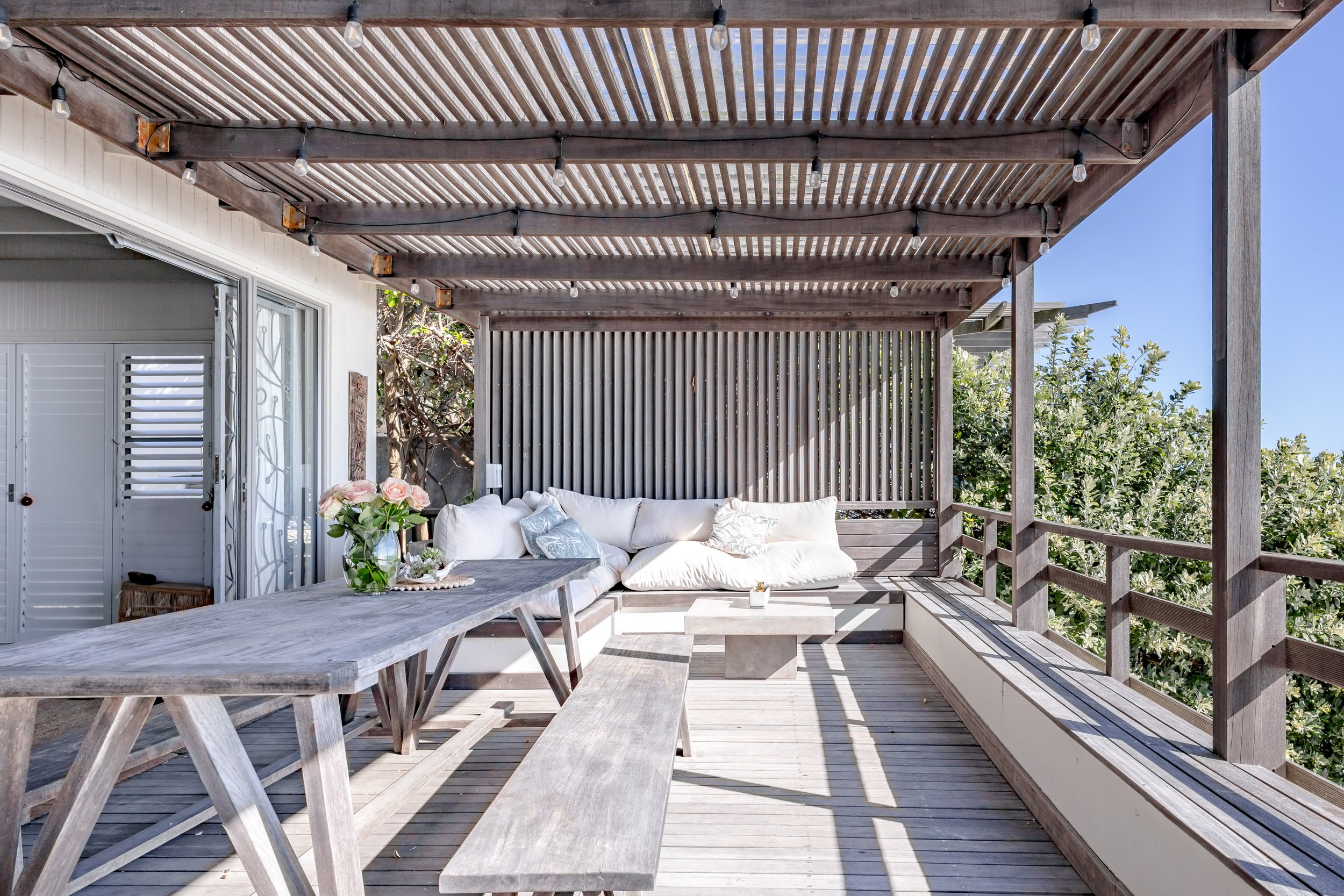 Shaded outdoor lounge area with comfortable white cushions and rustic wooden beams for alfresco relaxing.