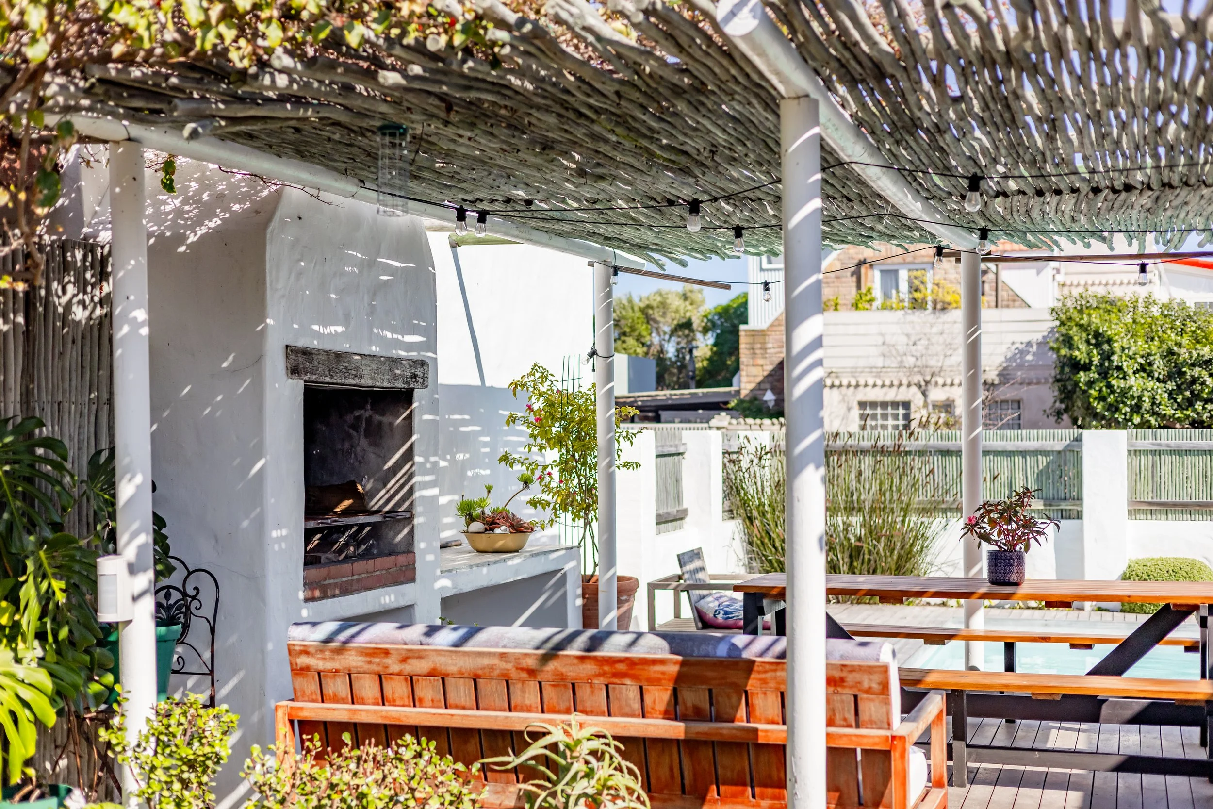 Outdoor entertainment area with covered dining space and built-in fireplace, photographed to showcase the lifestyle of a Cape Town holiday rental.