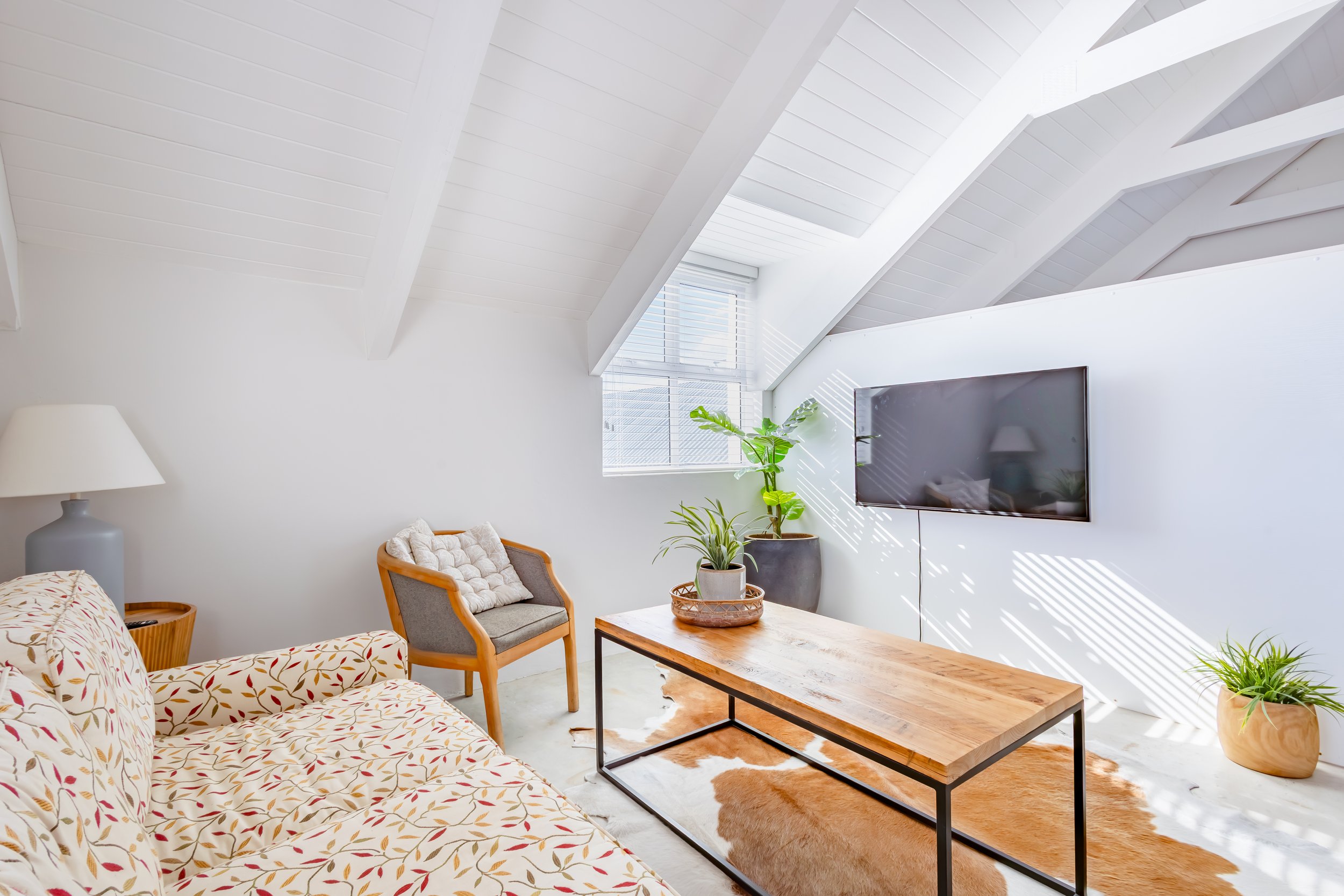 Cozy lounge area with a view of a flat-screen TV and indoor plants, highlighting the lifestyle and comfort of a professionally staged property.