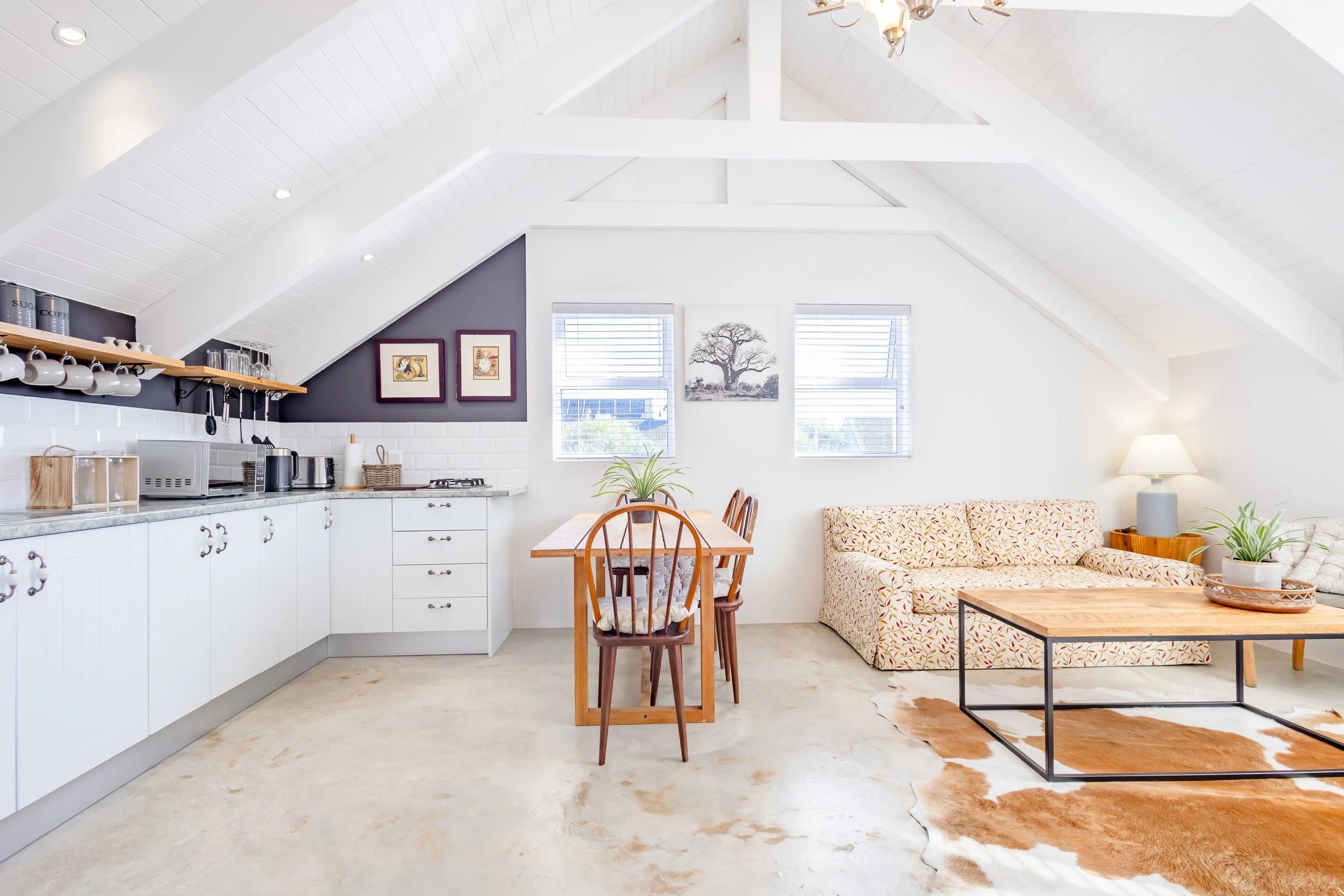 Symmetrical shot of a modern kitchen and living space, emphasizing the high-quality finishes and professional lighting used in property photography.