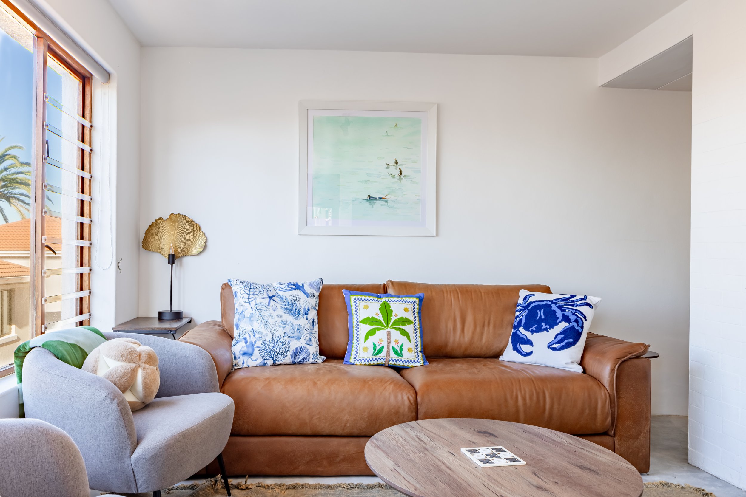 Professionally photographed coastal apartment living area featuring comfortable seating, ocean-inspired décor and natural light in St James, Cape Town.