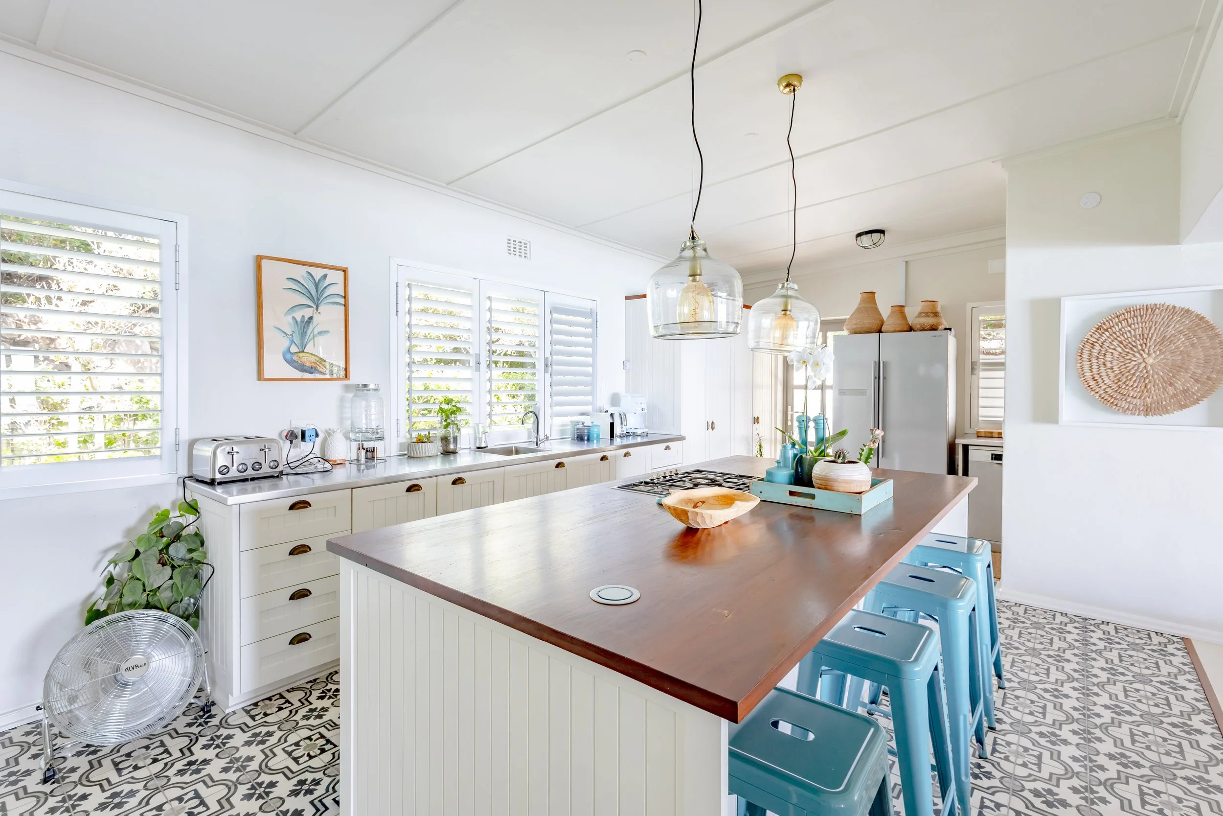 Fully equipped kitchen with a large wooden island, turquoise bar stools, and modern appliances for a self-catering stay.