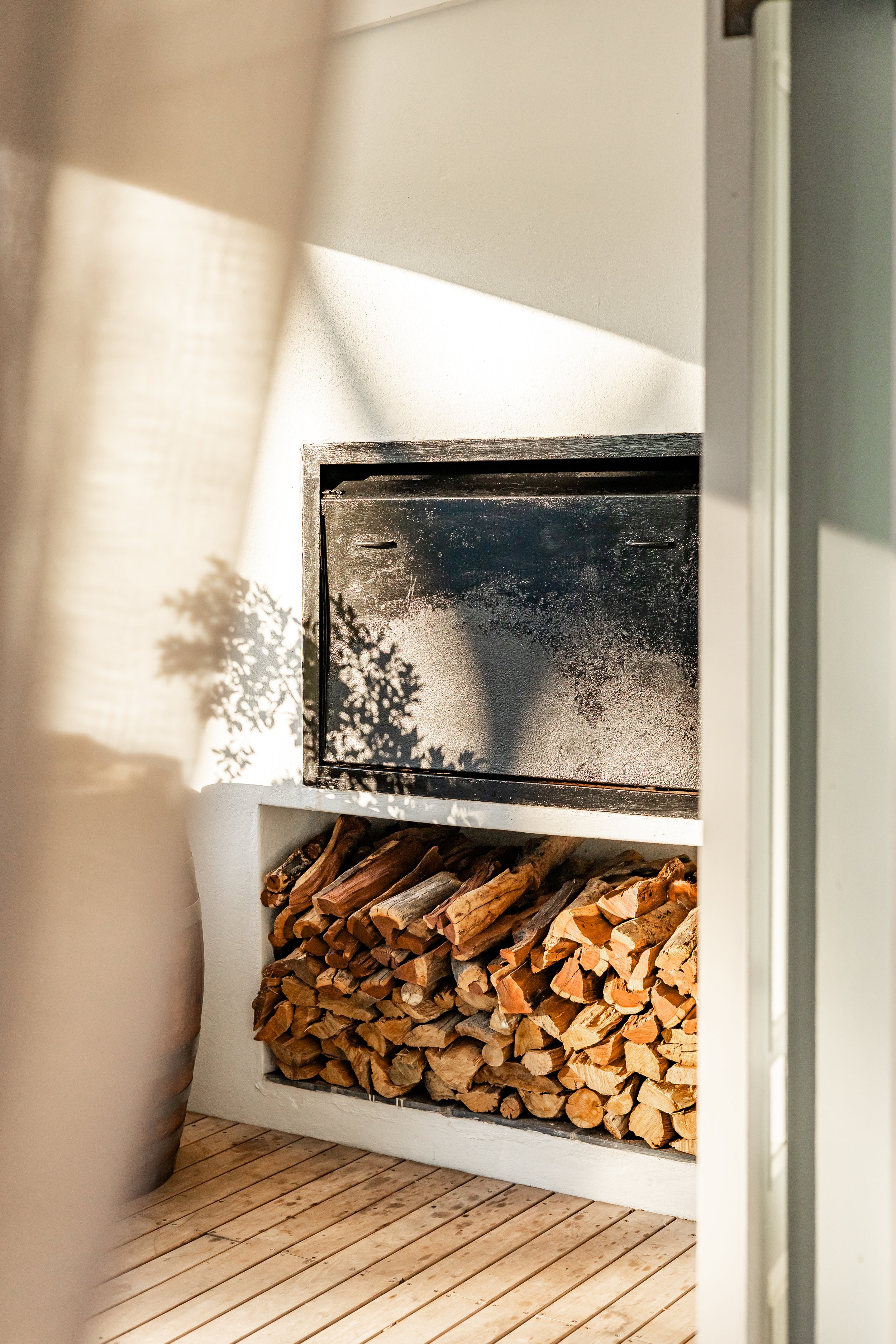 Detail photograph of an outdoor fireplace and stacked firewood at a luxury Airbnb property in Cape Town's Deep South.