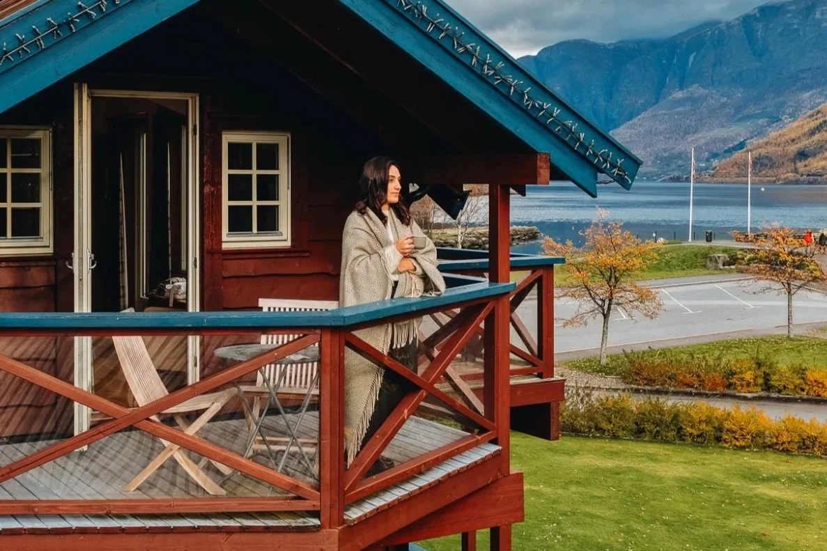 Woman enjoying her coffee at the Flåmsbrygga Hotell balcony overlooking the fjord