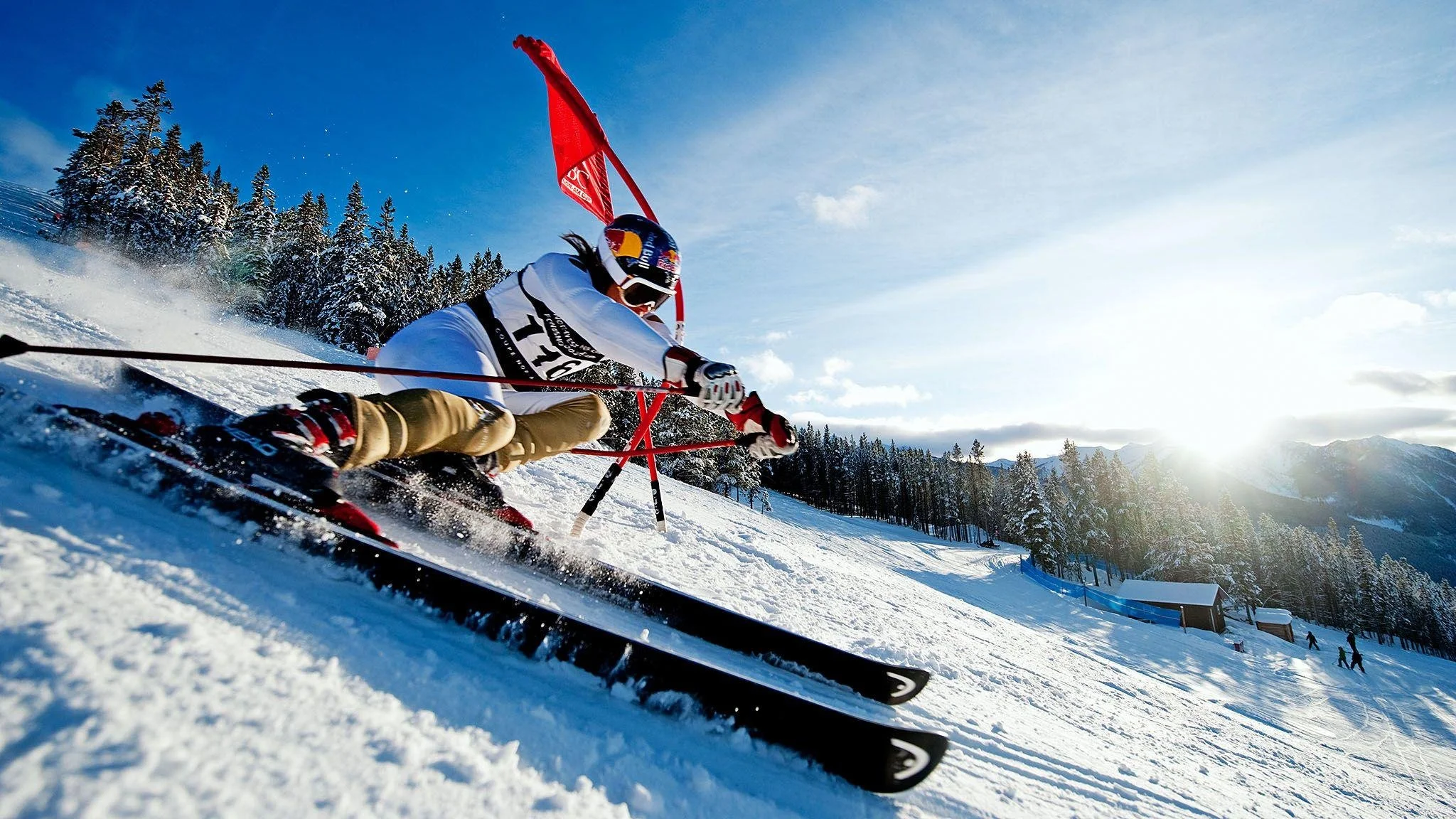 Alpine racer rounding a red gate on a sunny slope, illustrating gate training on the Kirkwood Ski Education Foundation website