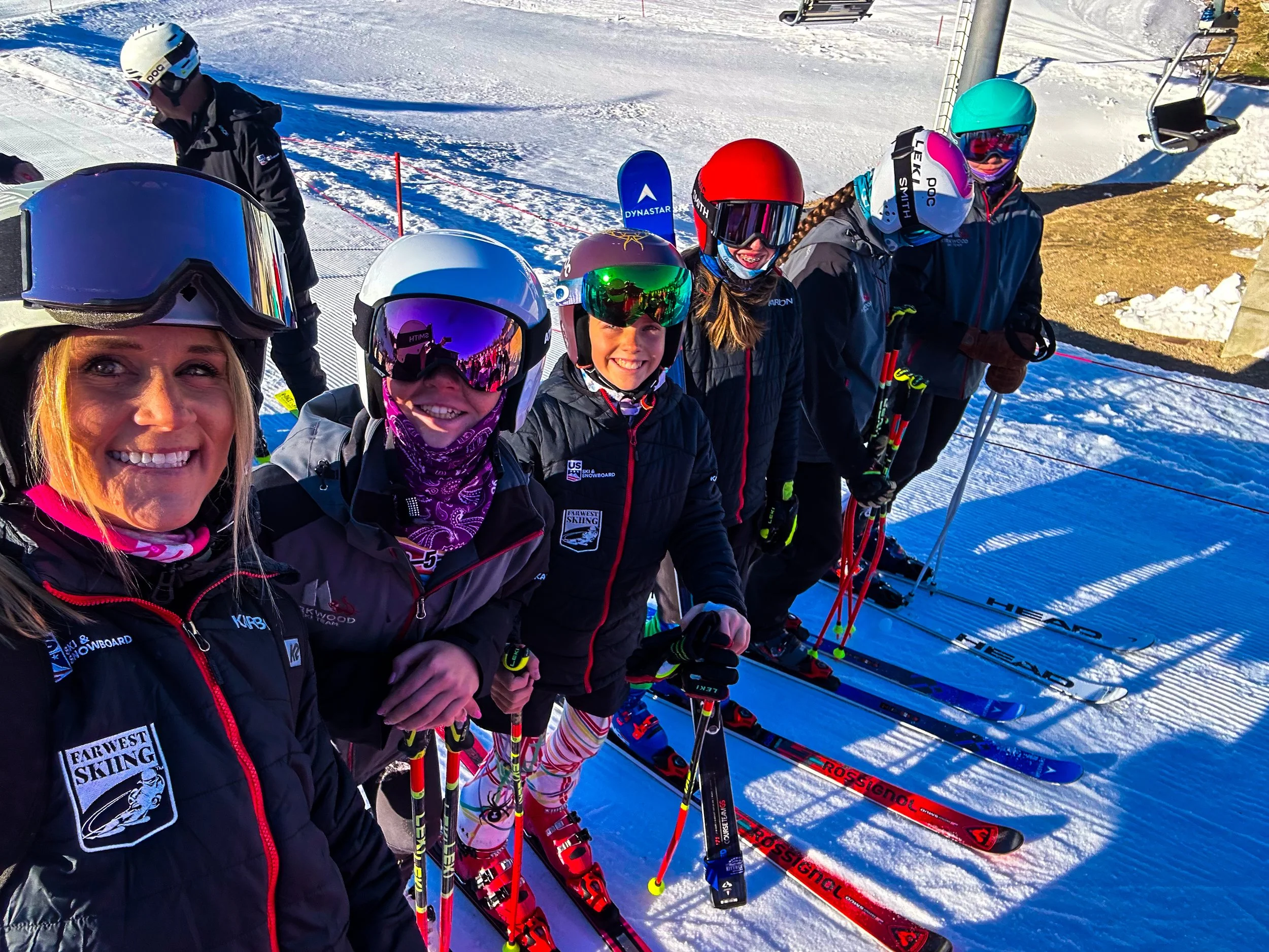 Kirkwood Ski Education Foundation coach and young athletes smiling in helmets and goggles on the snow