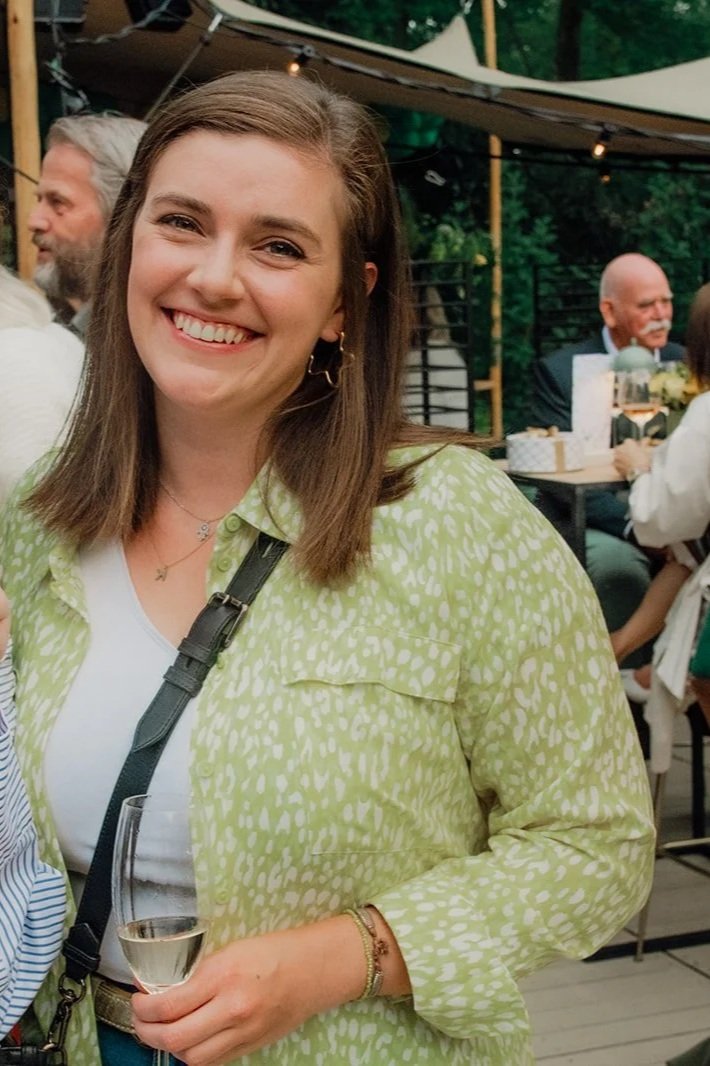 Twee vrouwen lachen en drinken champagne op een buitenfeestje.