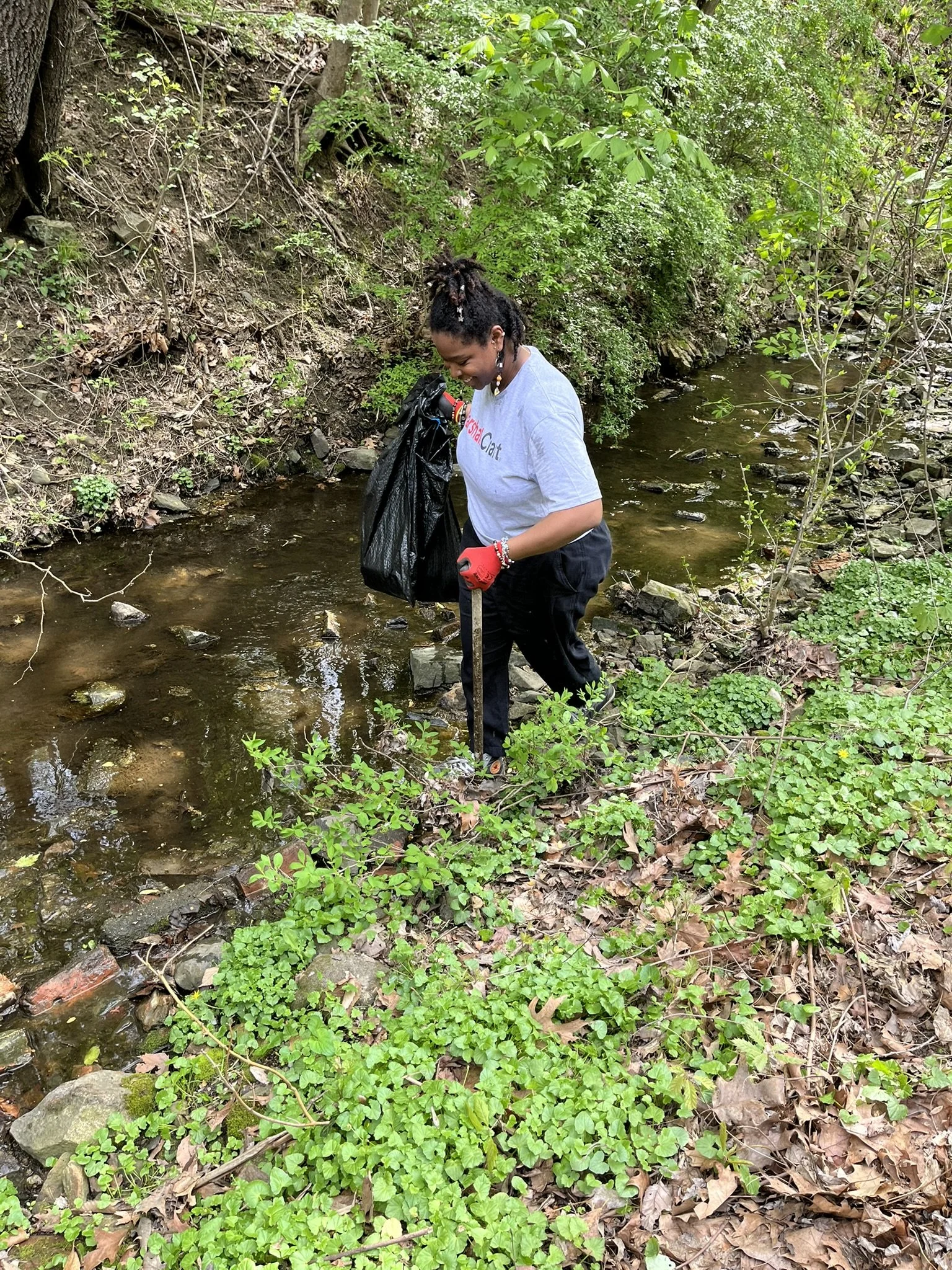 Lilleana searches for trash in the Jones Falls stream that surrounds the Baltimore office in Clipper Mill.