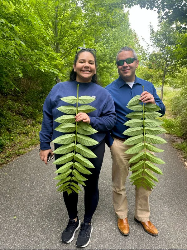 Frank and Karen smile holding branches on Richmond's 2026 Earth Day nature walk.