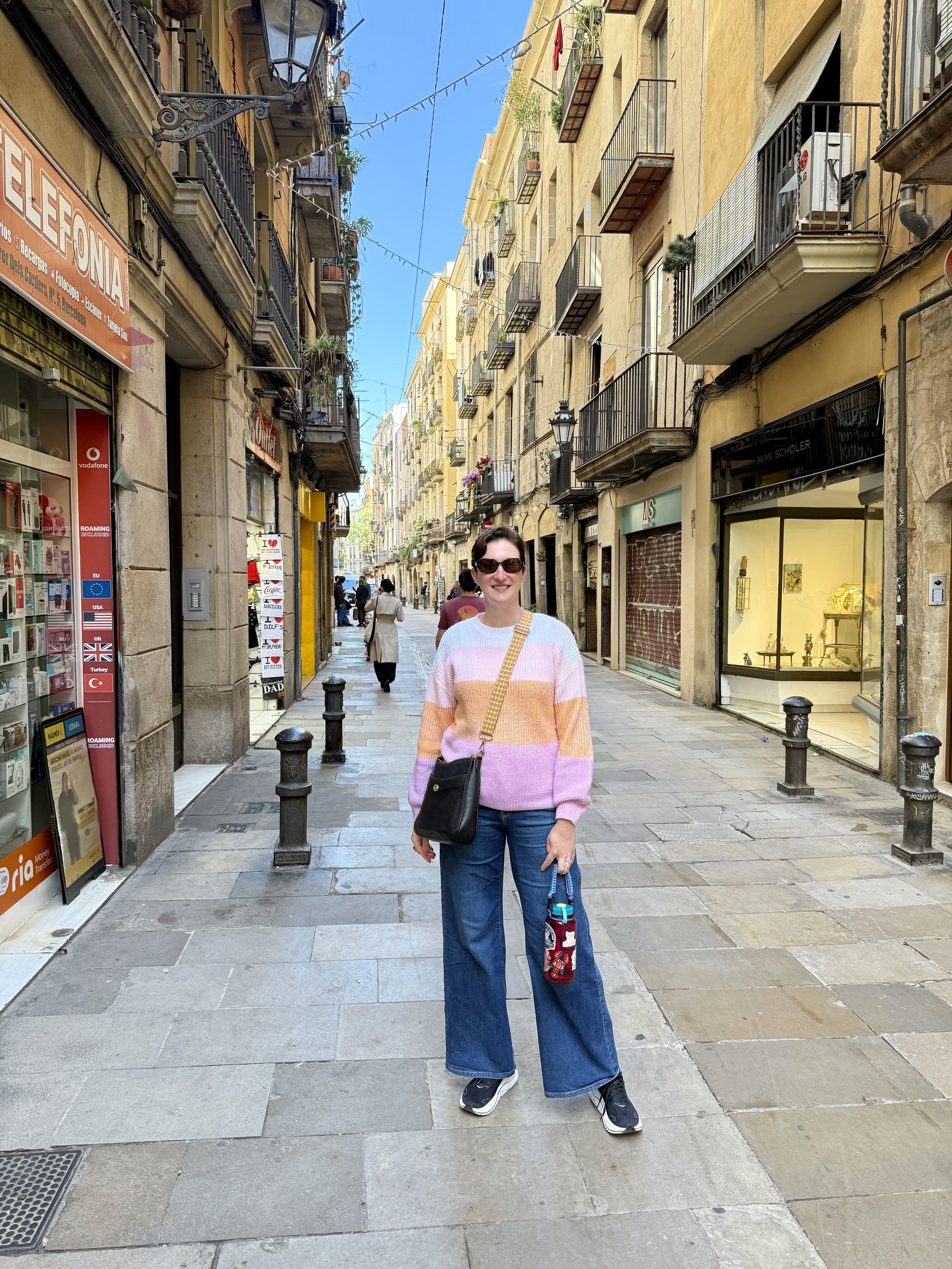 Woman in pink sweater on Barcelona Gothic Quarter street with shops