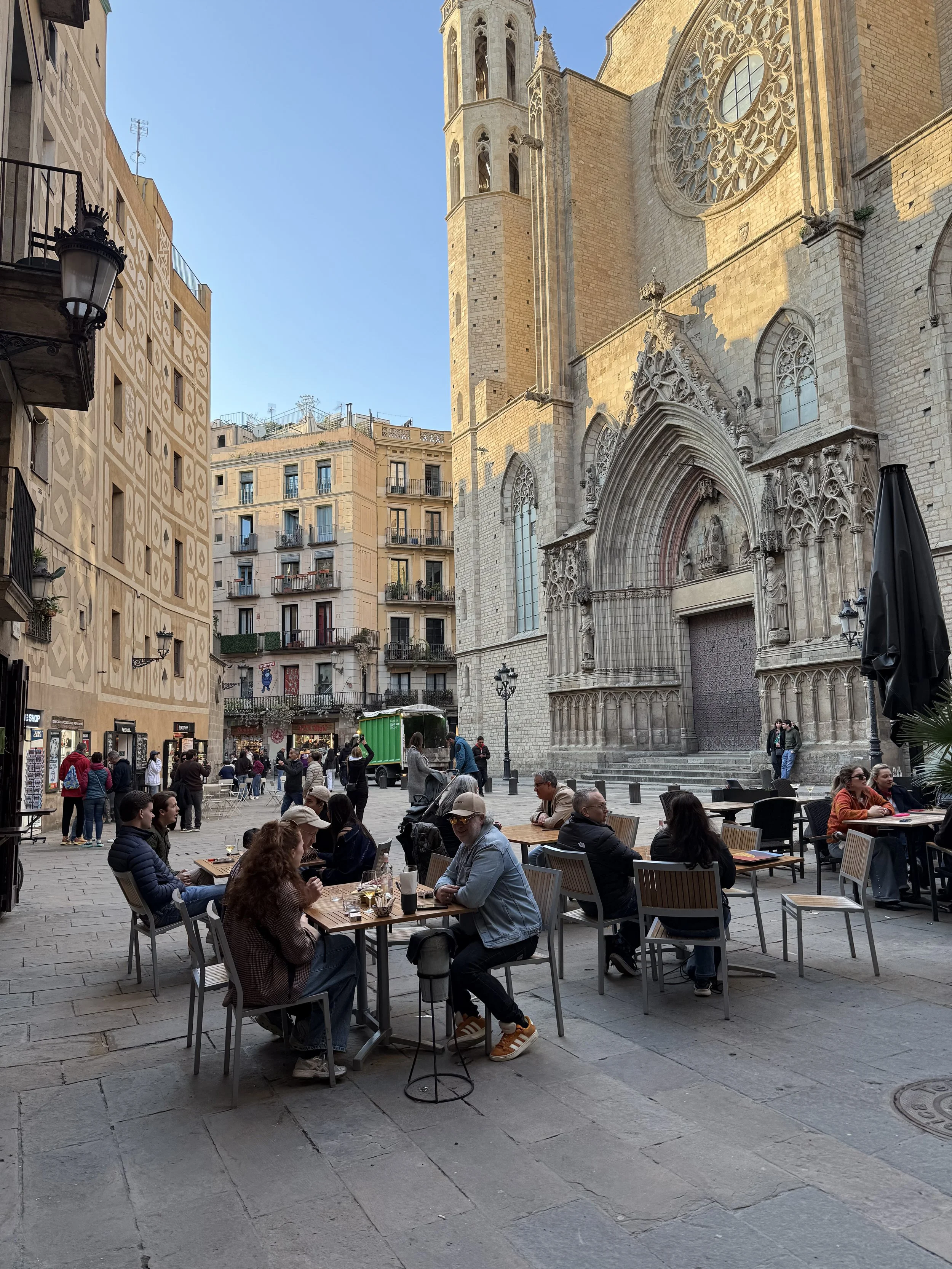 Outdoor café tables in Gothic quarter plaza with Santa Maria del Mar church in background