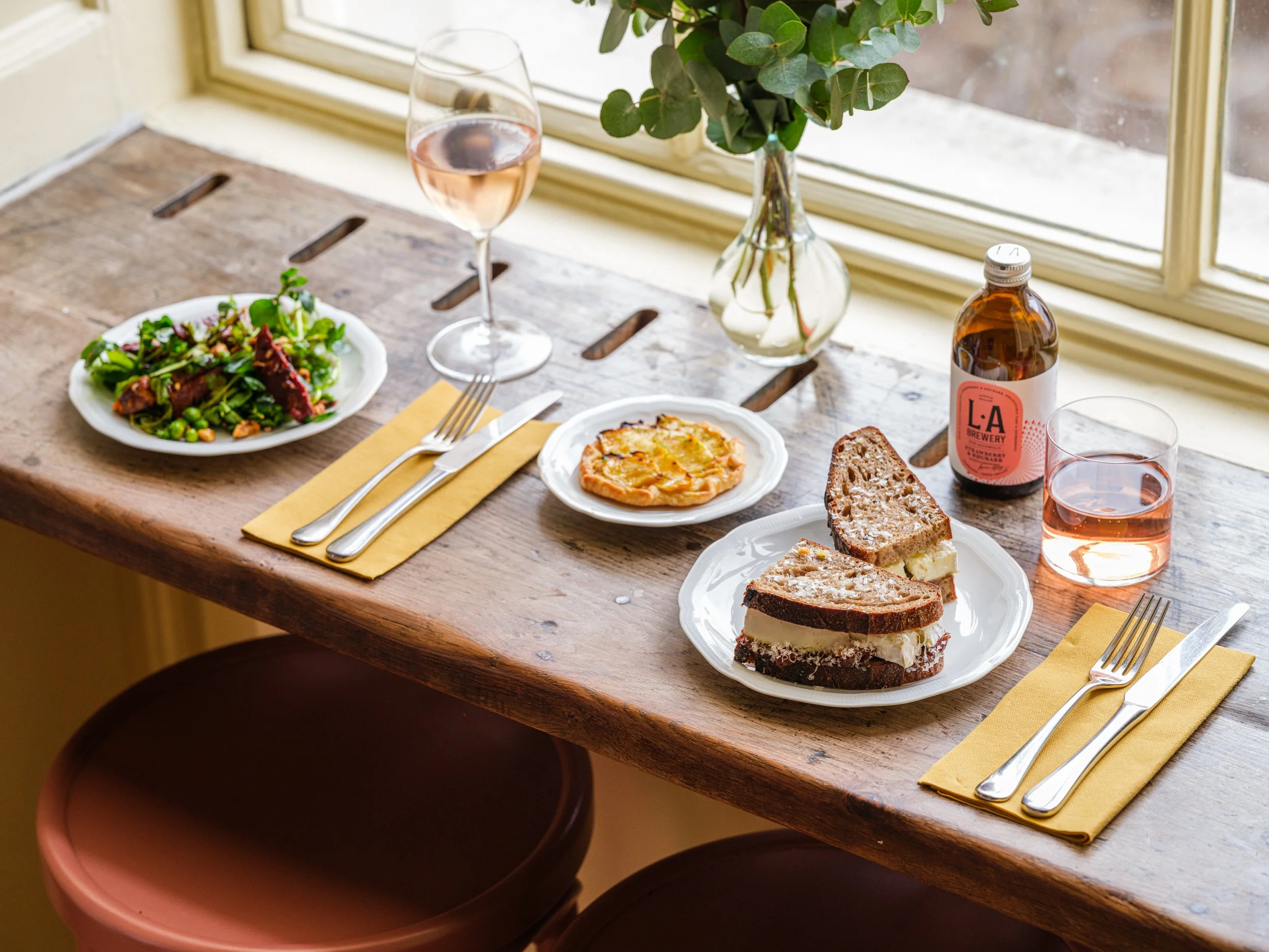 A window table set for a plant-first lunch by a sunny window at Cafe Petiole Somerset House, London