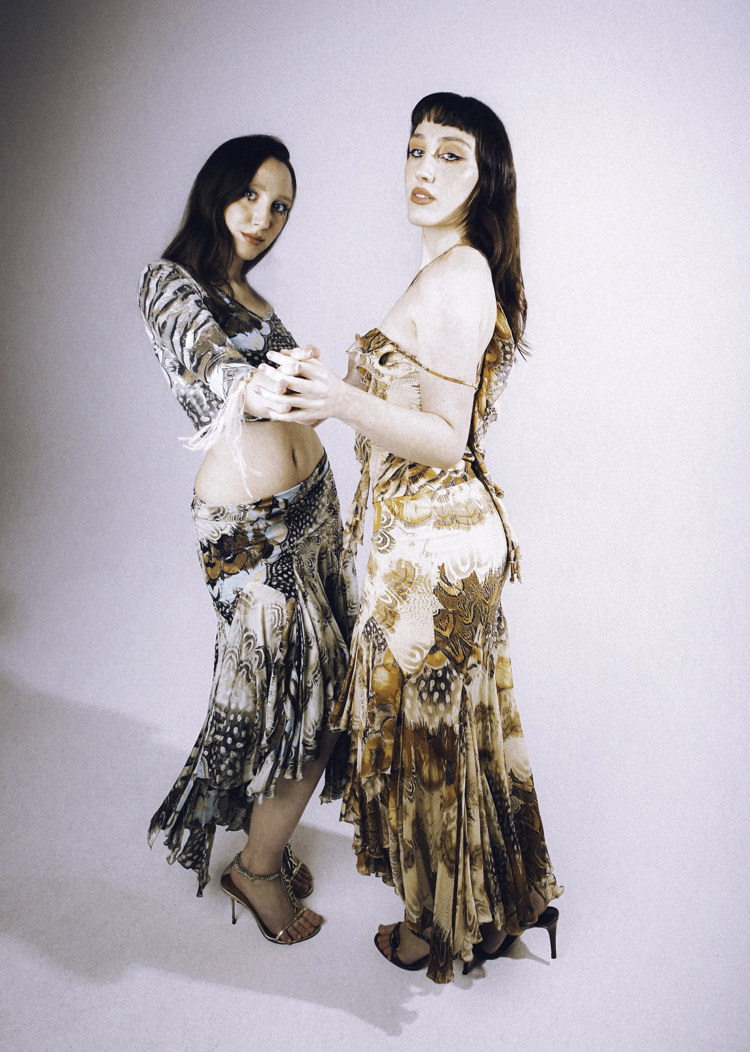 Two models in patterned slip dresses posing together against a white backdrop. Vintáááge March by Hartenjager.