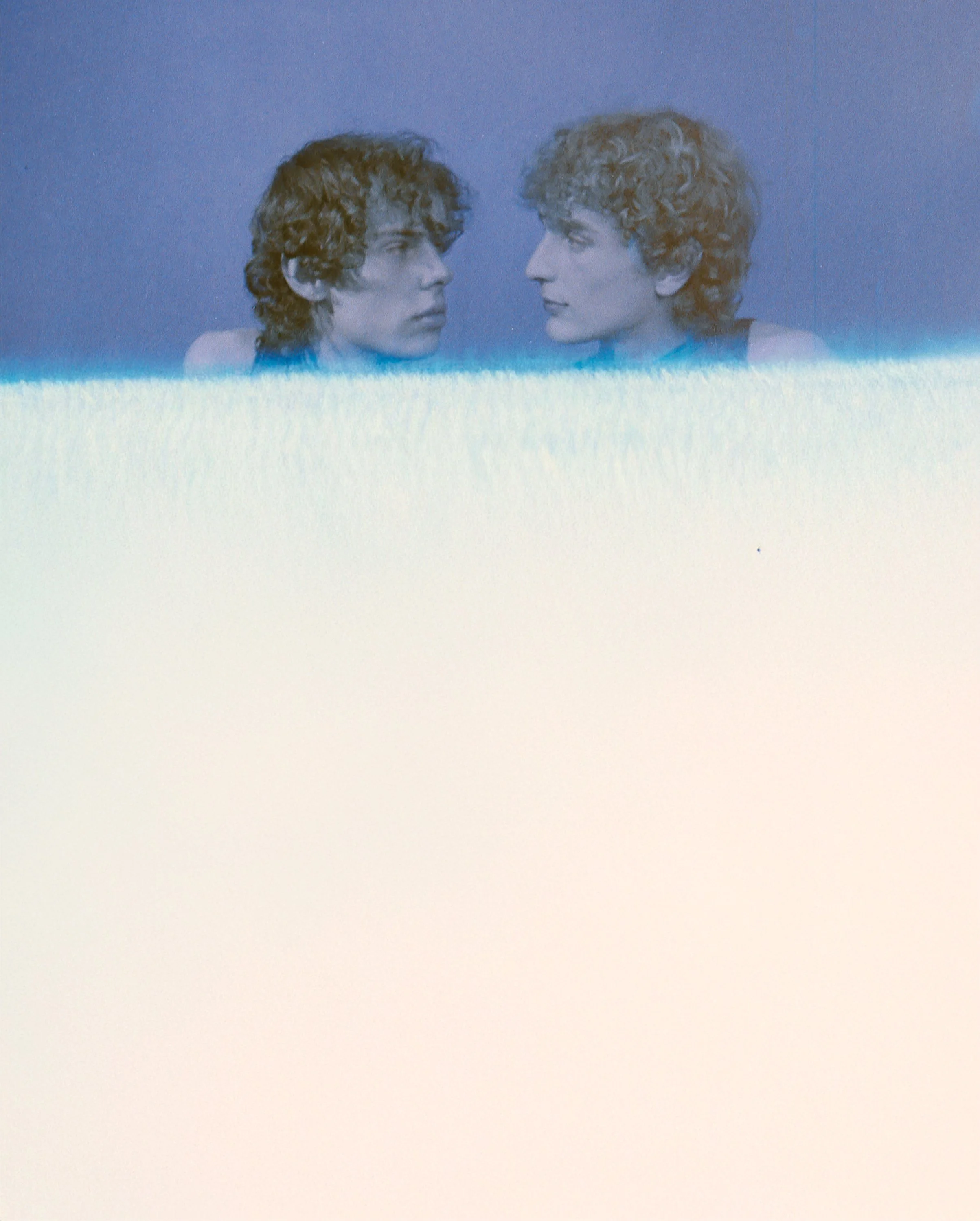 Two curly-haired faces mirroring each other at the top of a washed-out frame. Geminus by Hartenjager.