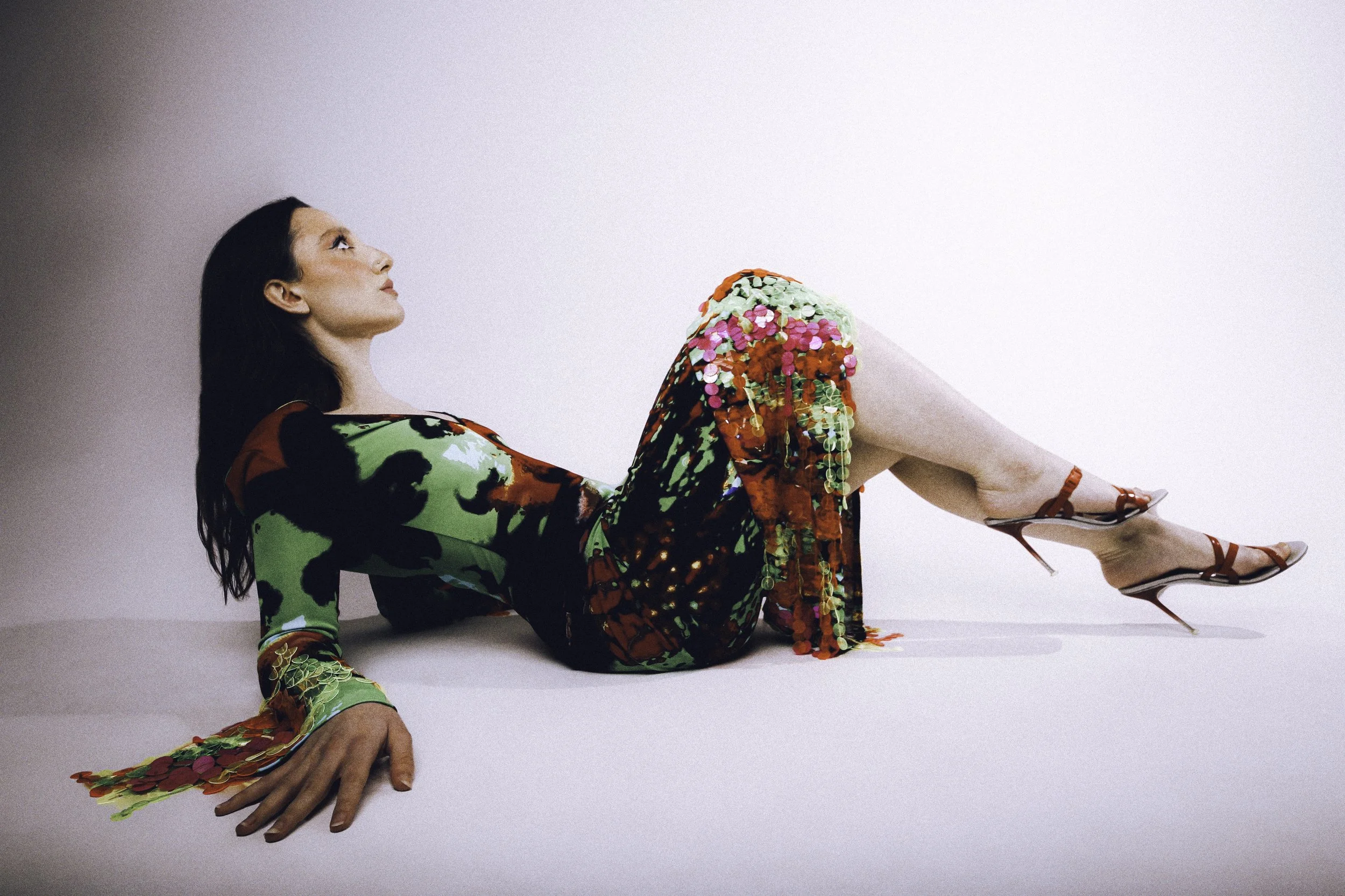 Model with long dark hair lying on the floor in a green floral set and strappy heels. Vintáááge March by Hartenjager.