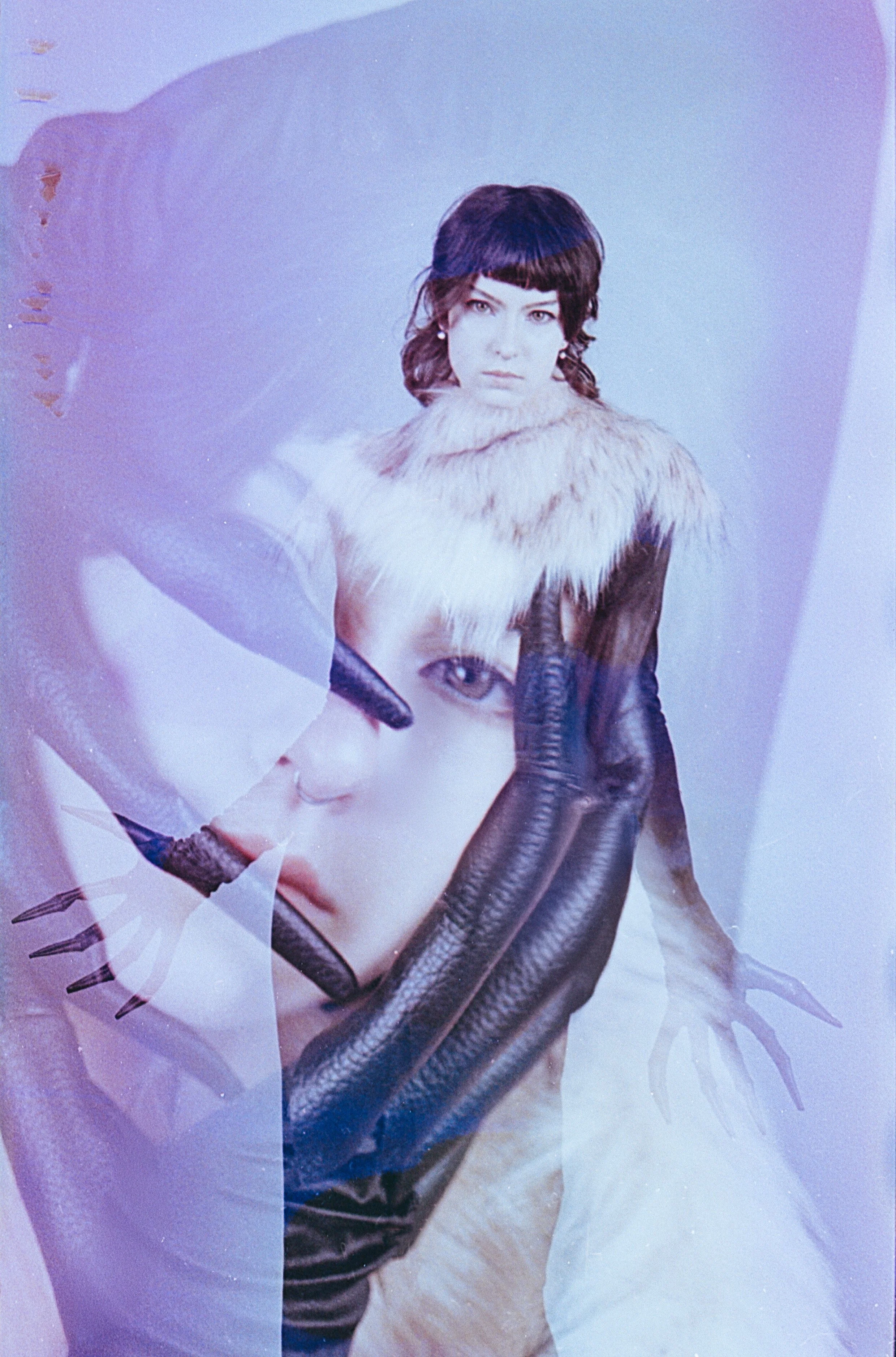 Model in a white fur stole and black opera gloves, the film eaten into pale purple patches. Acidic Mutations by Hartenjager.
