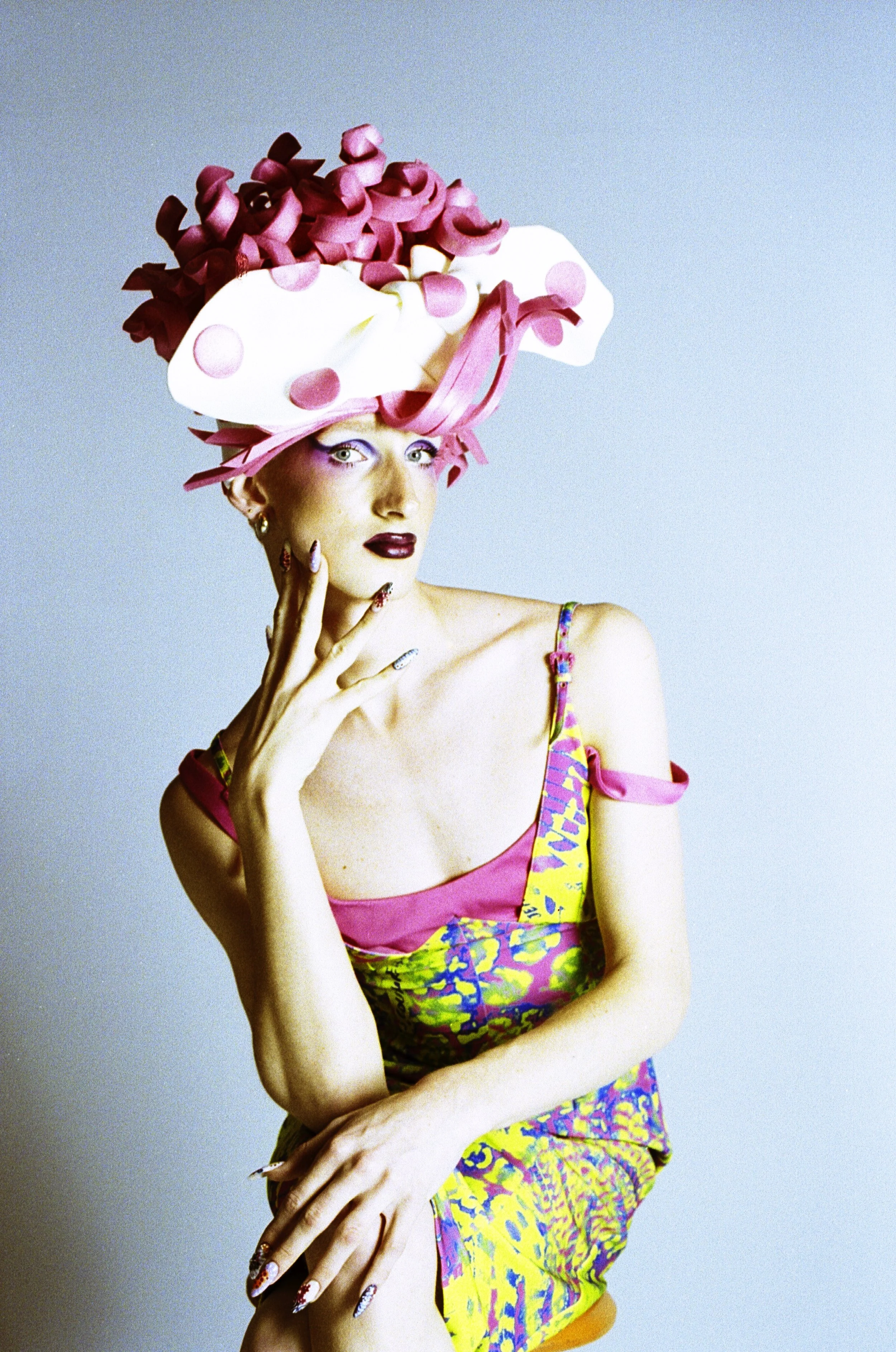 Model in a sculpted pink and white wig, floral top and 2000s styling, hand to their chin. Loopsyland, editorial for Kaltblut Magazine by Hartenjager.