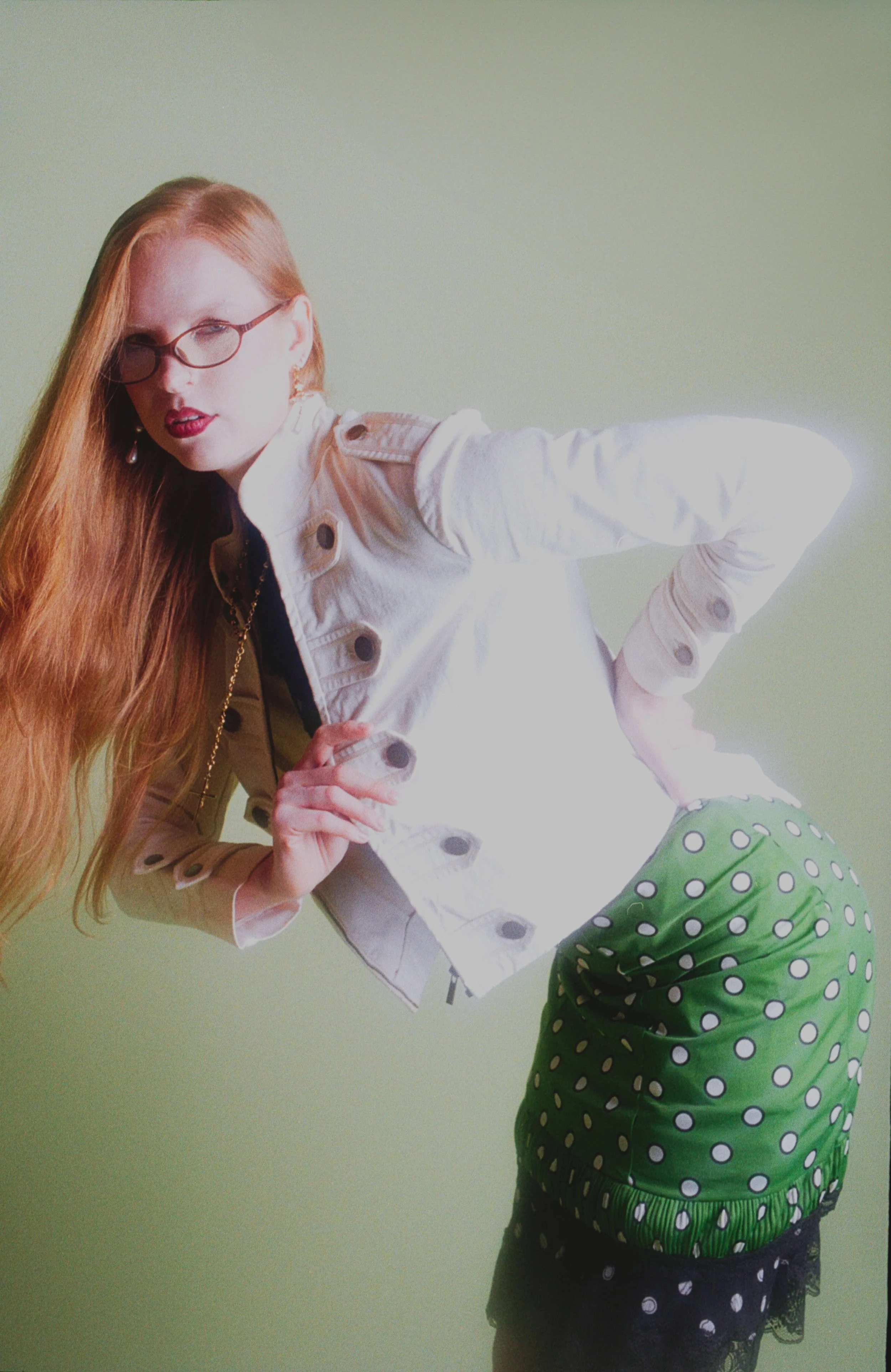 Red-haired model with glasses in a cream cardigan, pulling at the collar. Vintáááge May by Hartenjager.
