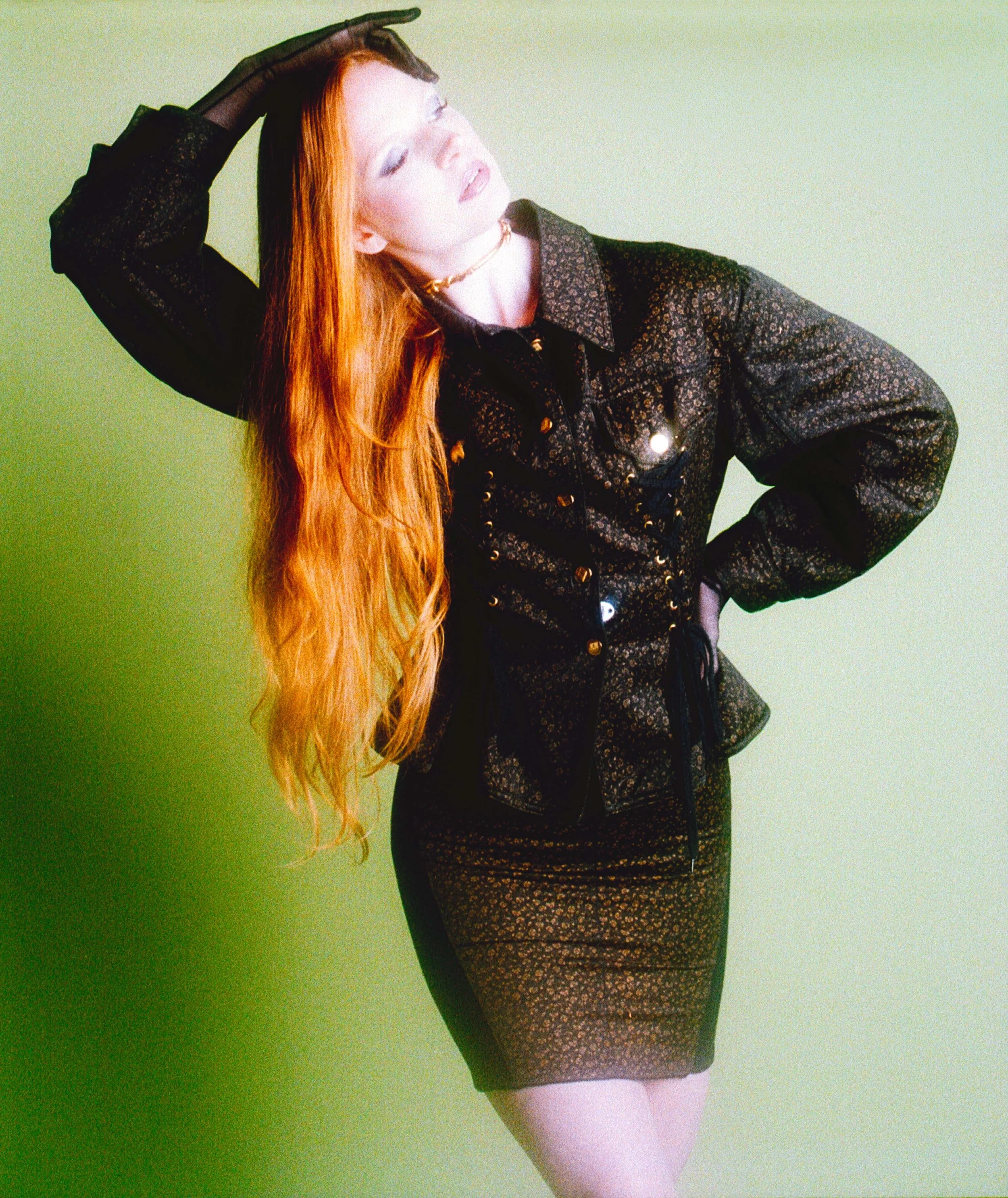Red-haired model in a studded black jacket, one gloved hand on her head. Vintáááge May by Hartenjager.