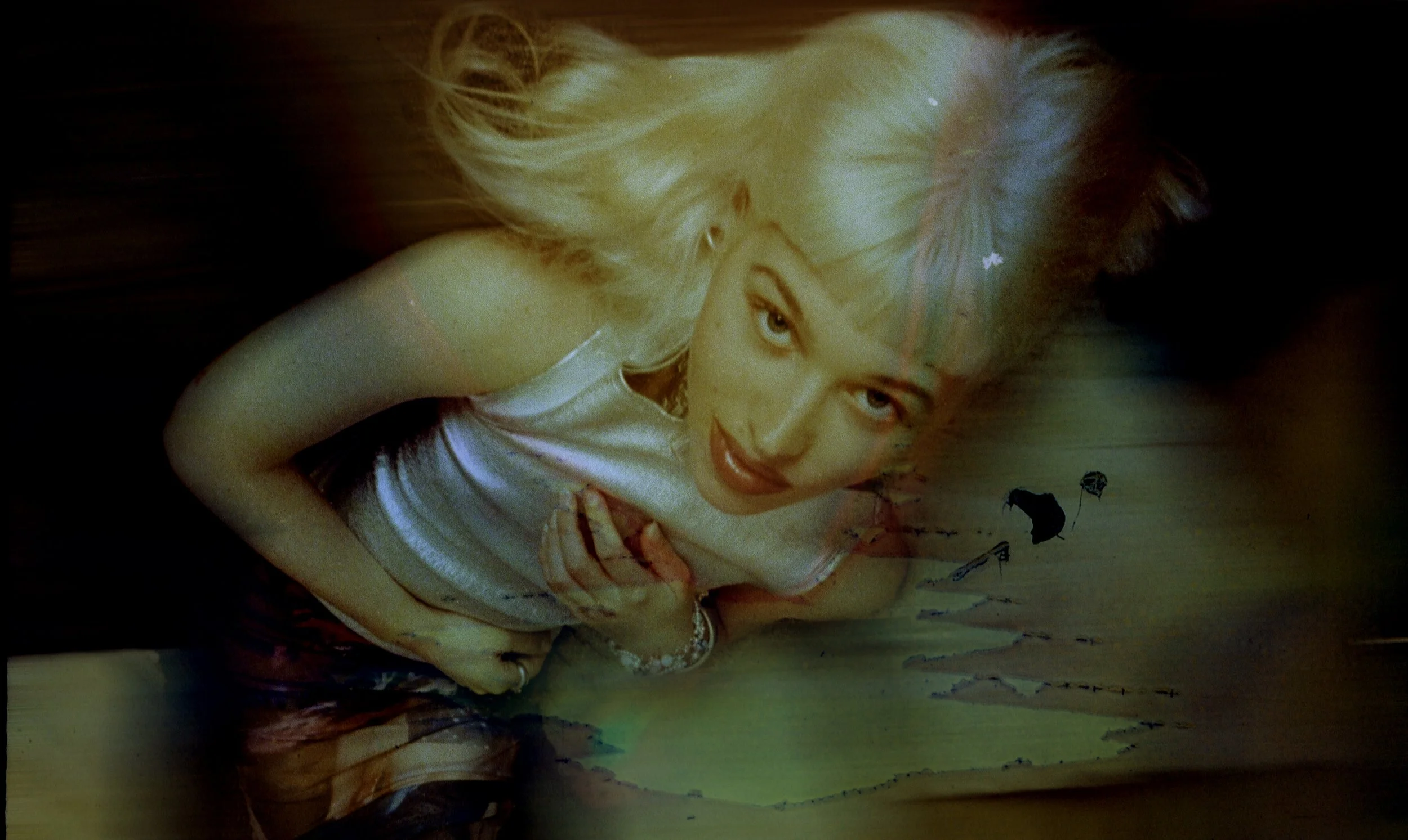 Blonde model in silver leaning toward the camera, her face glowing against a dark, light-leaked background. Bubblehead by Hartenjager.