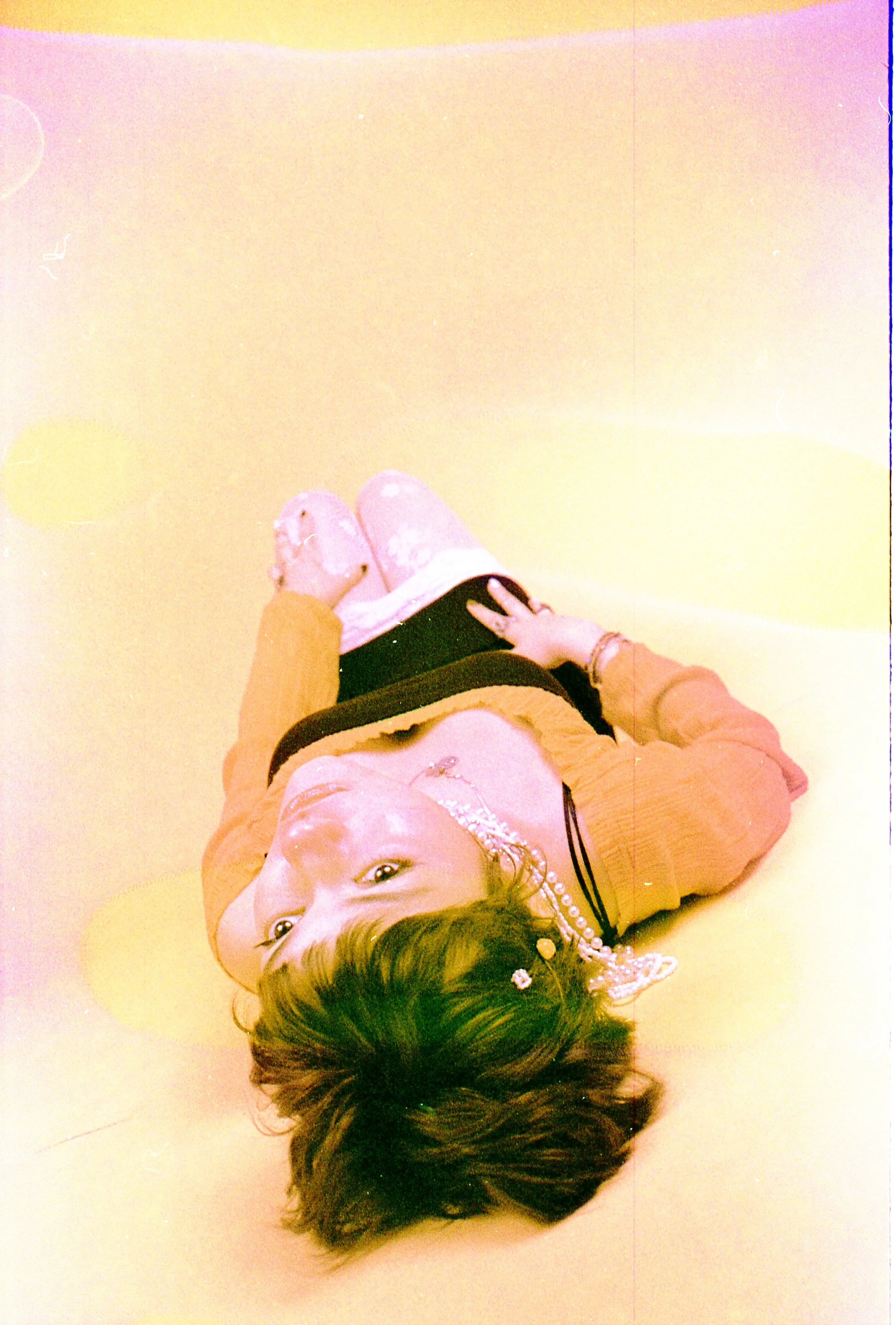 Upside-down portrait of a person lying on the floor in washed-out film soup colours. By Hartenjager.