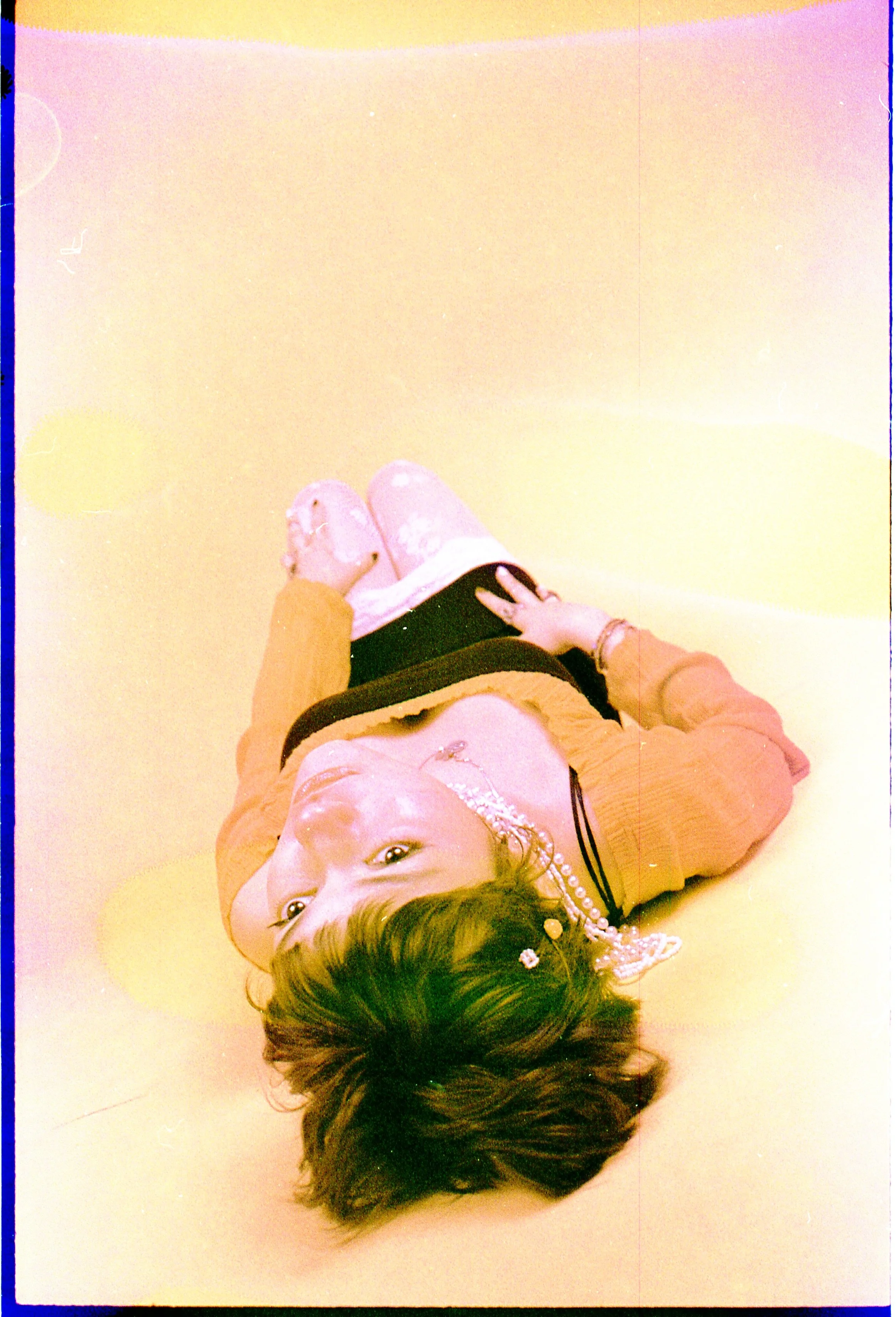 Person lying upside down on the floor in a sailor collar, washed out in yellow and pink film soup. Chemical Subscura by Hartenjager.