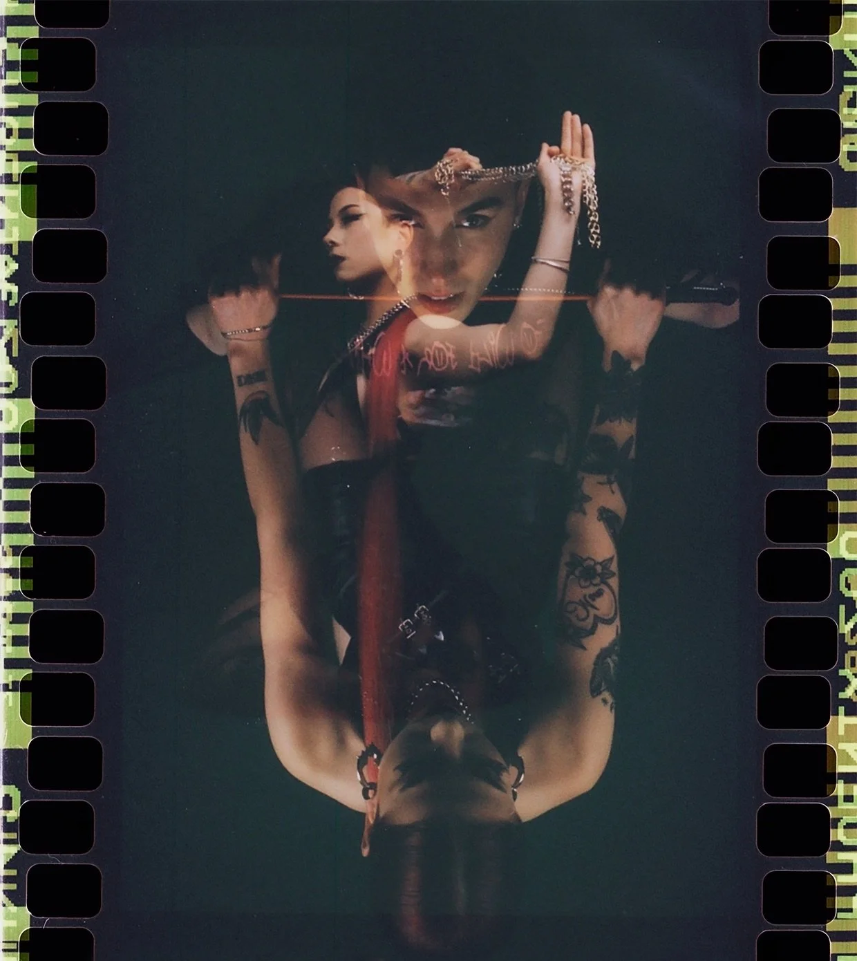 Film frame with sprocket holes: a double exposed figure in red and black lace, mirrored top to bottom. Dominance by Hartenjager.