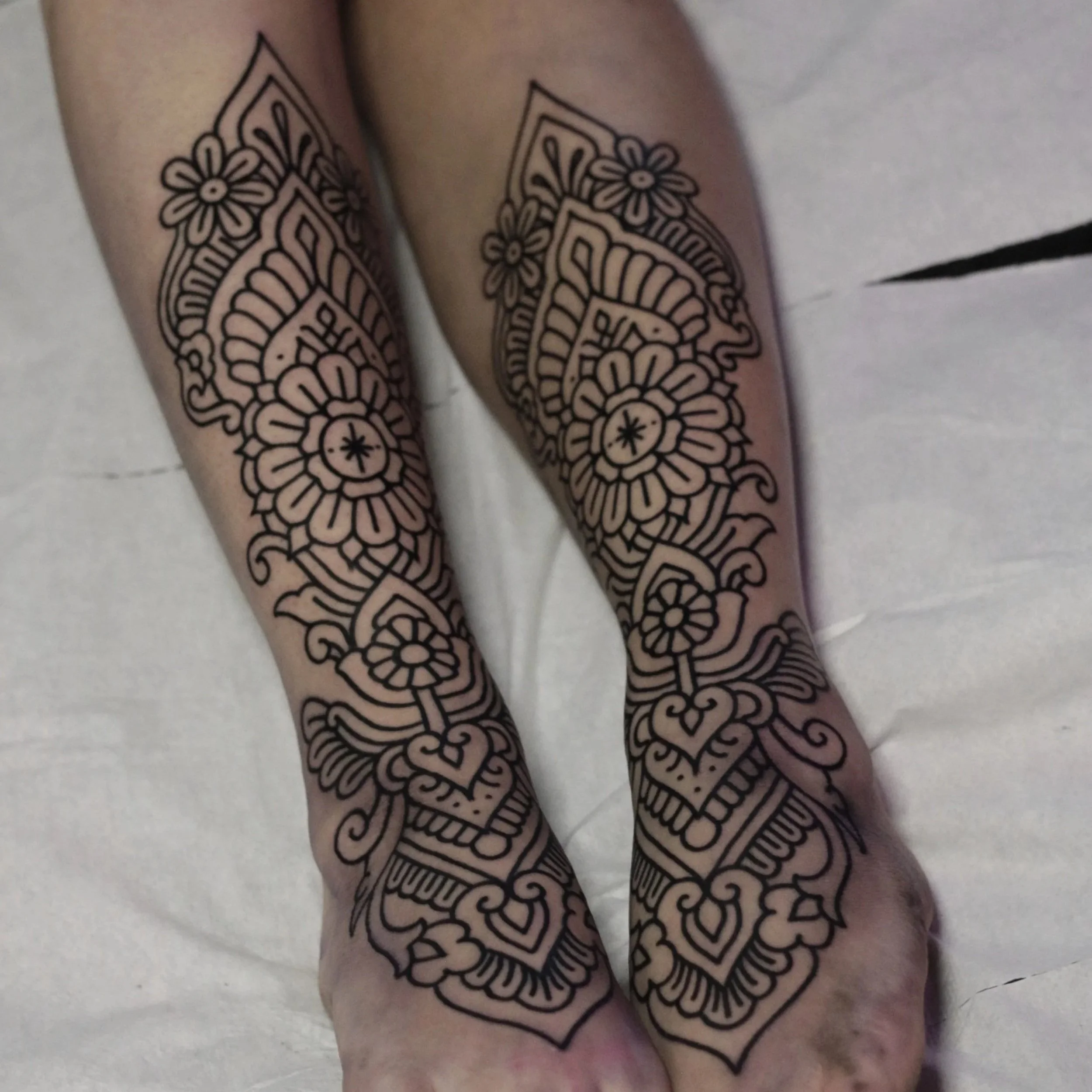 Henna and Mehndi style symmetric shin tattoos. Delicate hindi ornamental blackwork tattoo.