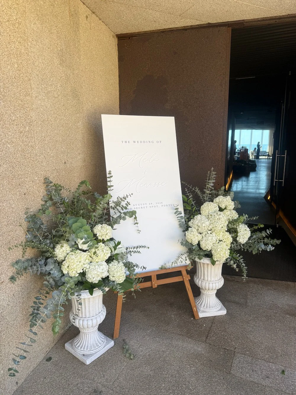 Wedding sign with white floral arrangements in urns at Secret Spot in Portugal, dated August 28, 2026.