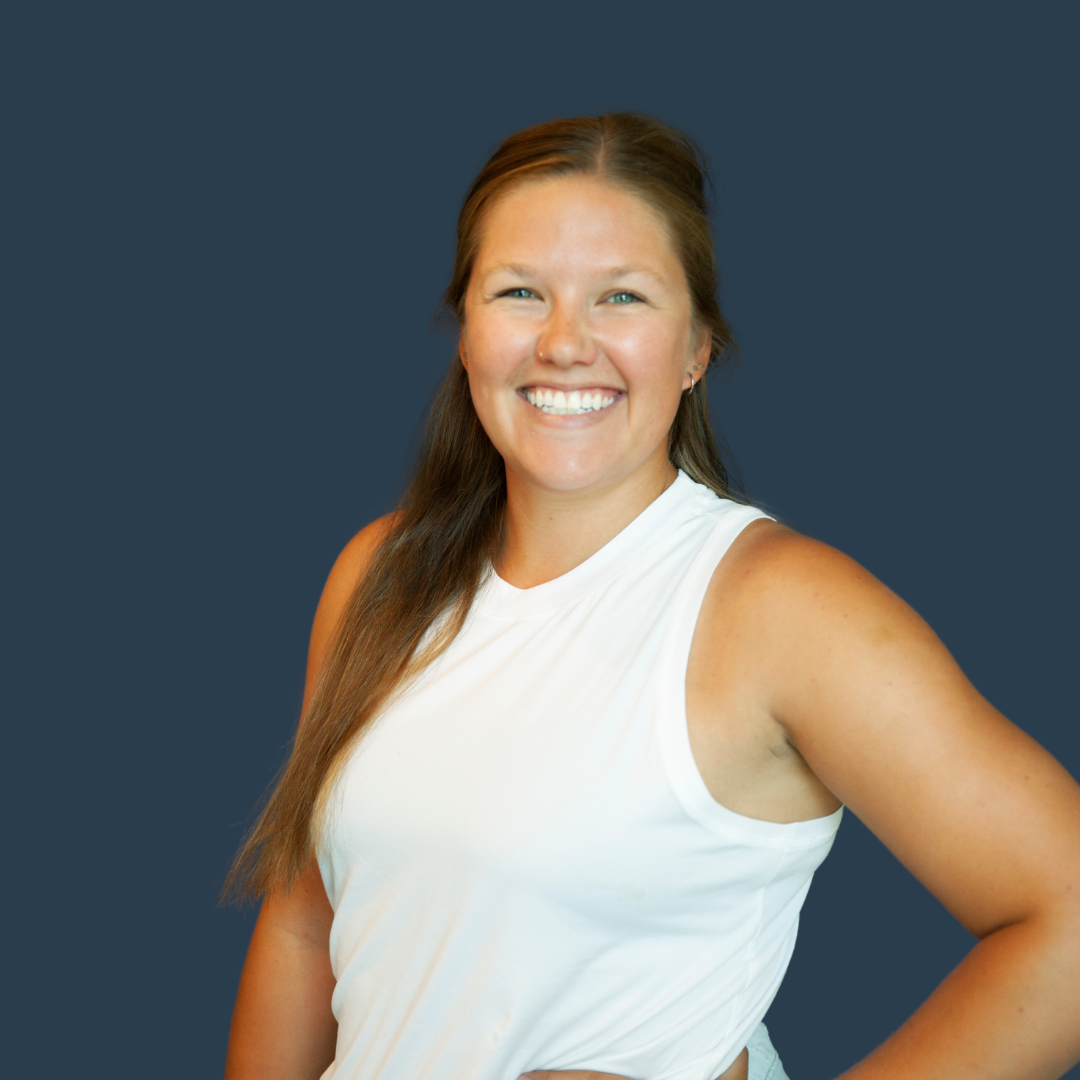Smiling person wearing a blue sweater against a dark background