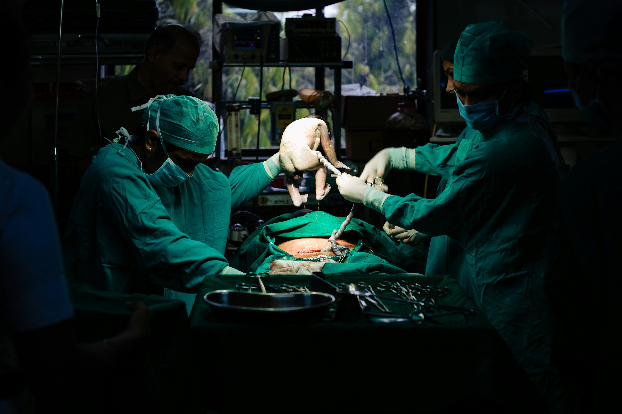 Two doctors supporting the birth of a baby by cesarean section.