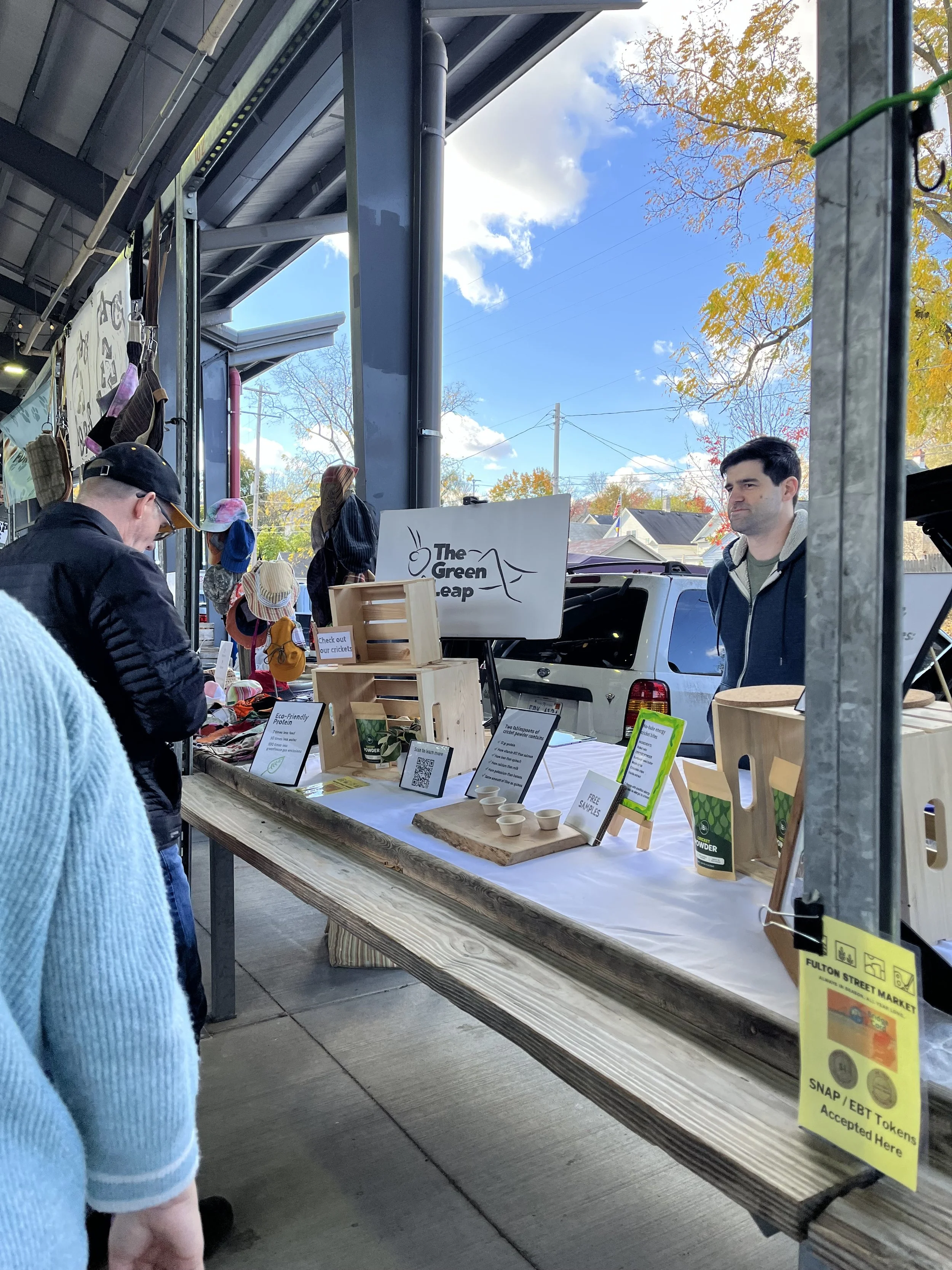 Owner, Henry, is pictured behind a table selling Cricket Powder at the Fulton Street Farmer's Market