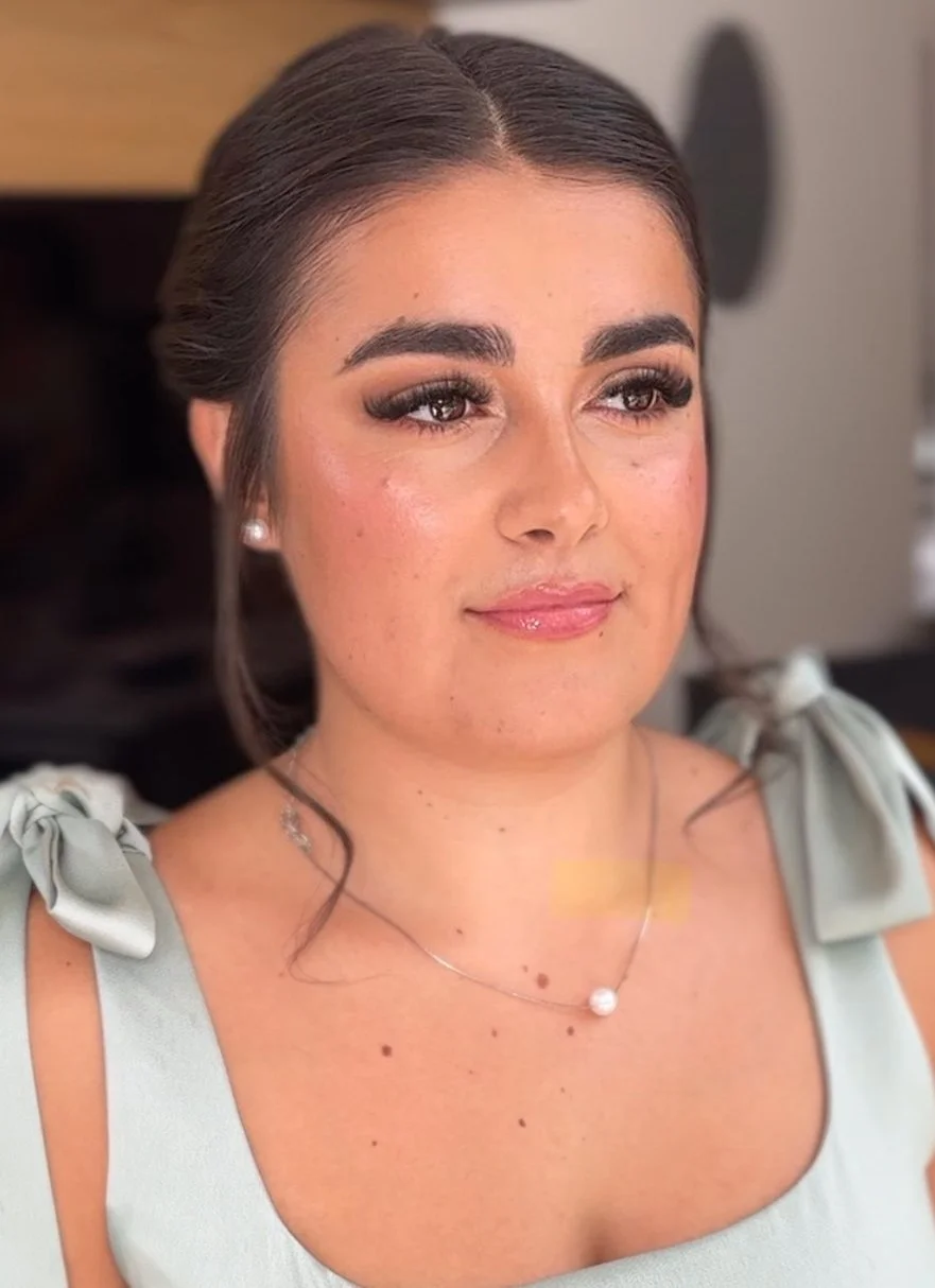 Woman with makeup, pearl necklace, and light green dress.
