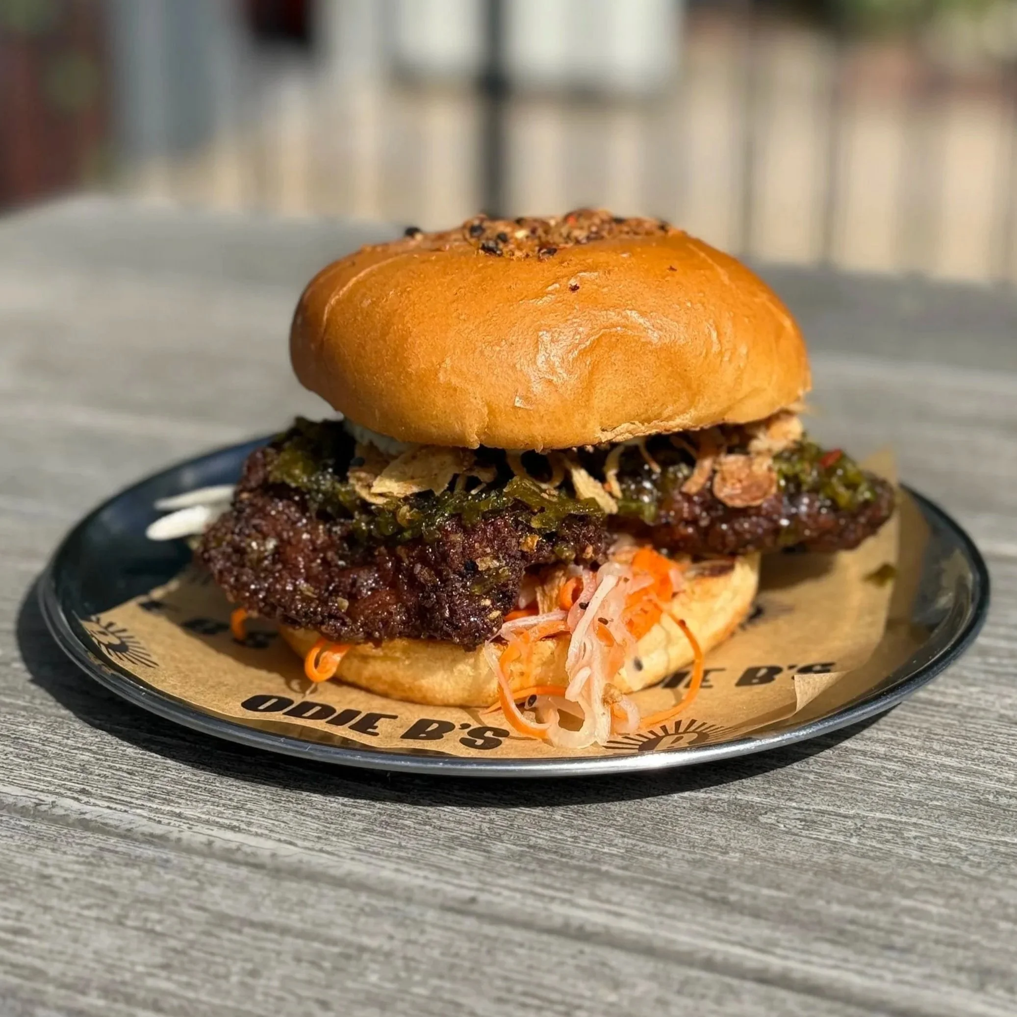 Beef sandwich with coleslaw on a black plate outdoors.