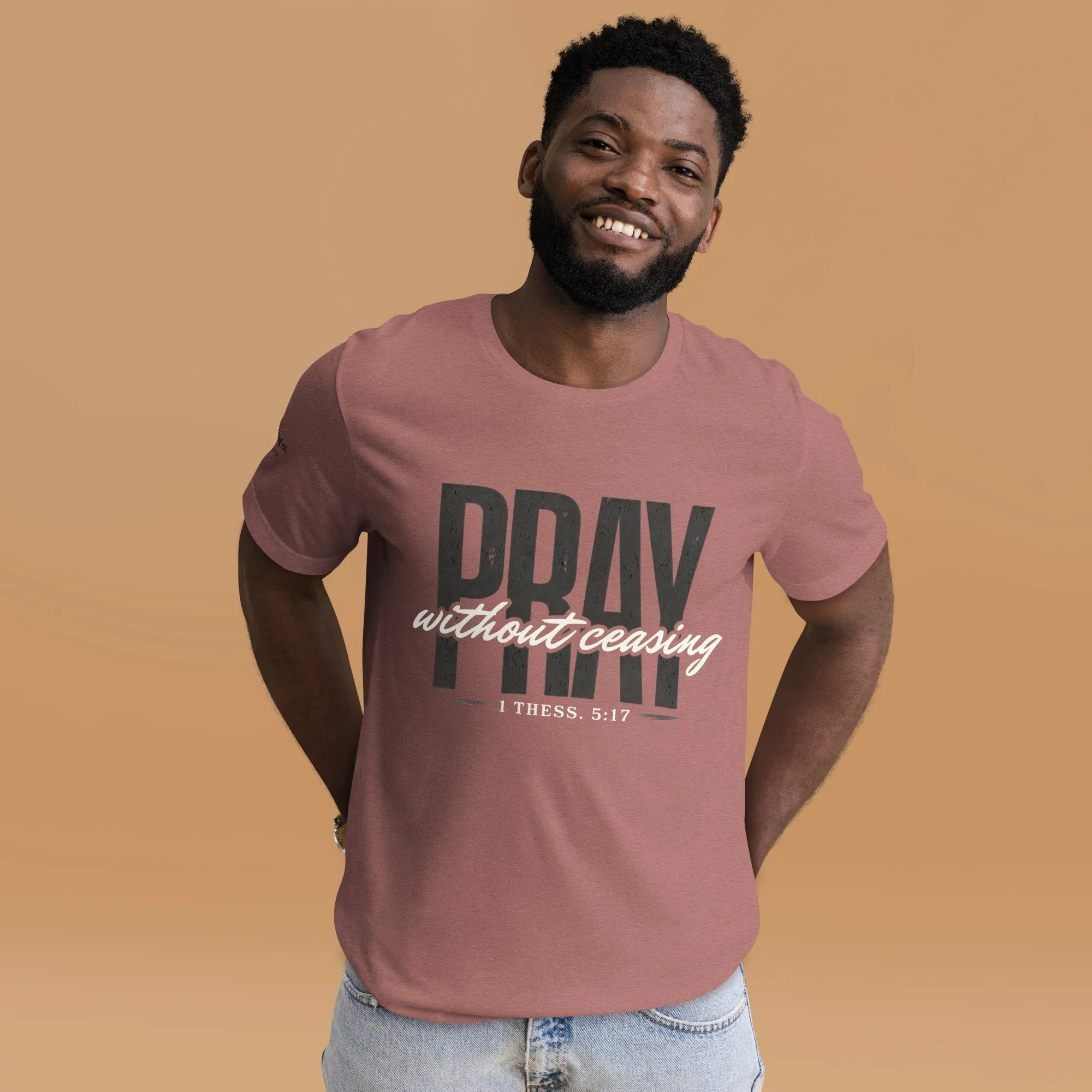 A man wearing a peach colored t-shirt that reads, "Pray without ceasing"