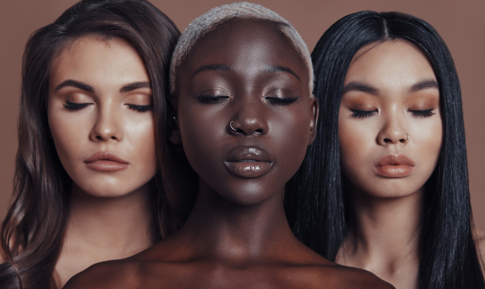Three women with eyes closed, diverse skin tones, and shiny, styled hair, posing against a plain background.
