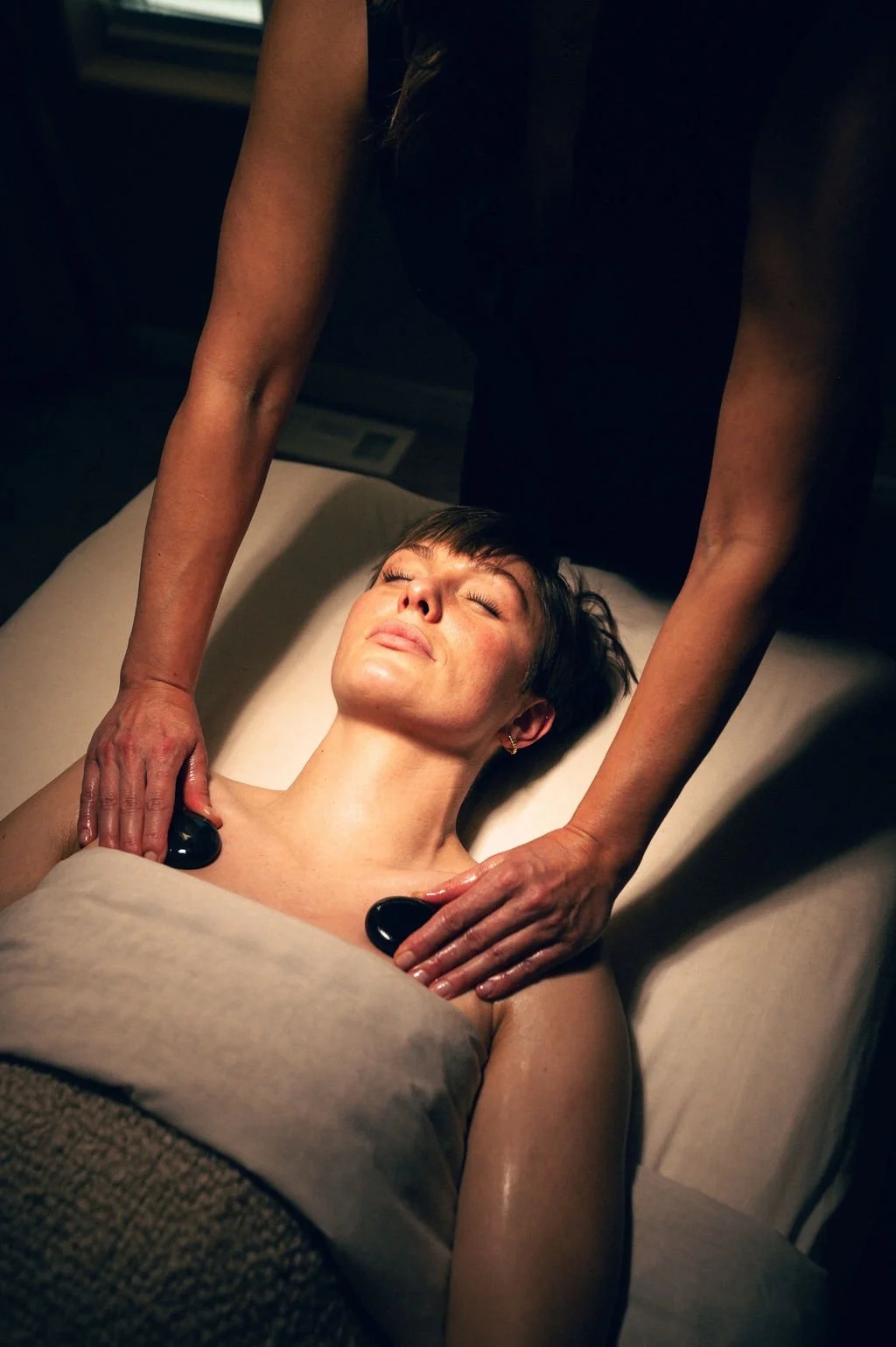Hot stone massage in Salt Lake City at Kalm Sanctuary, featuring heated stones used during full-body massage for deep relaxation and muscle relief