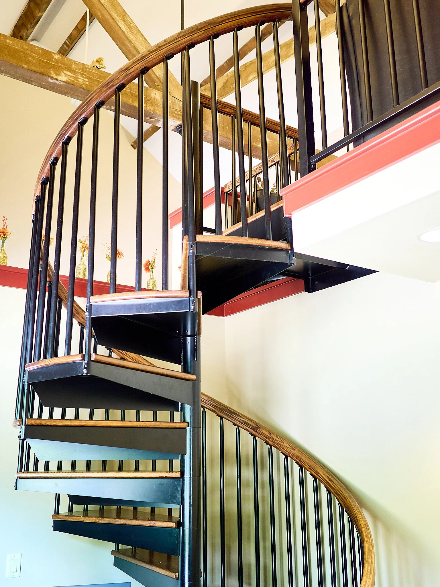 Spiral staircase with wood and metal railing inside a house.