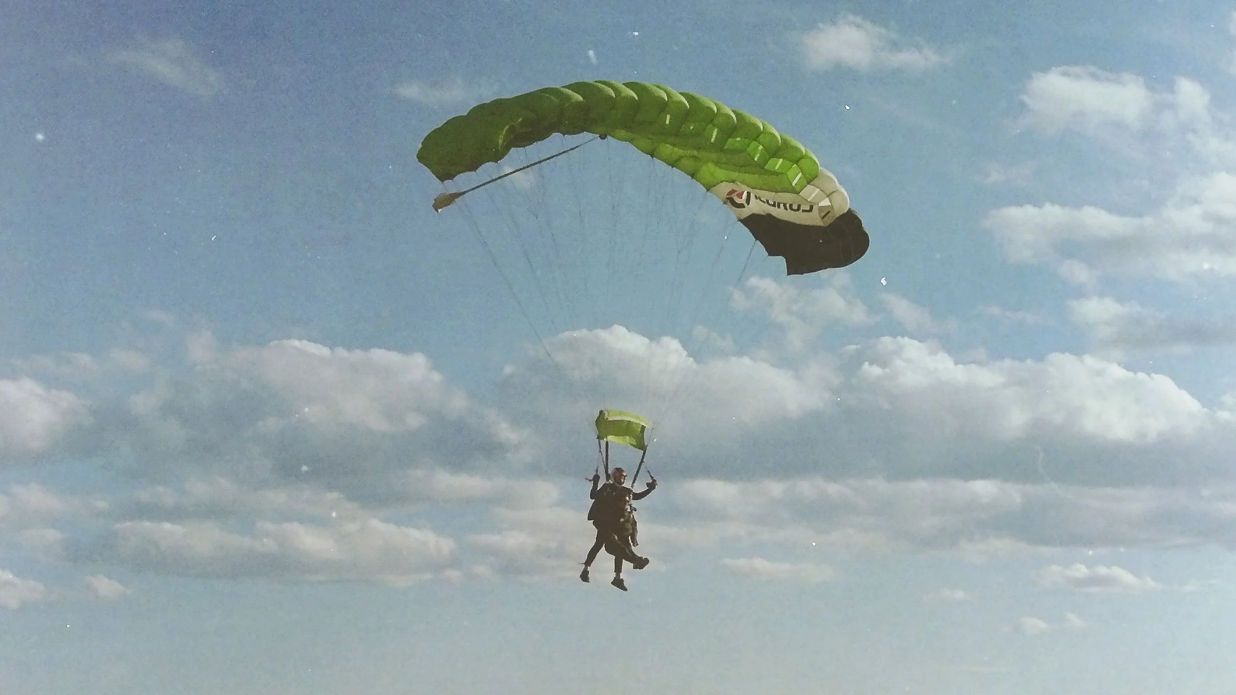 35mm film photo of a tandem skydiving pair flying a TX2 parachute on final approach with clouds in the background at Skydive Skydown.