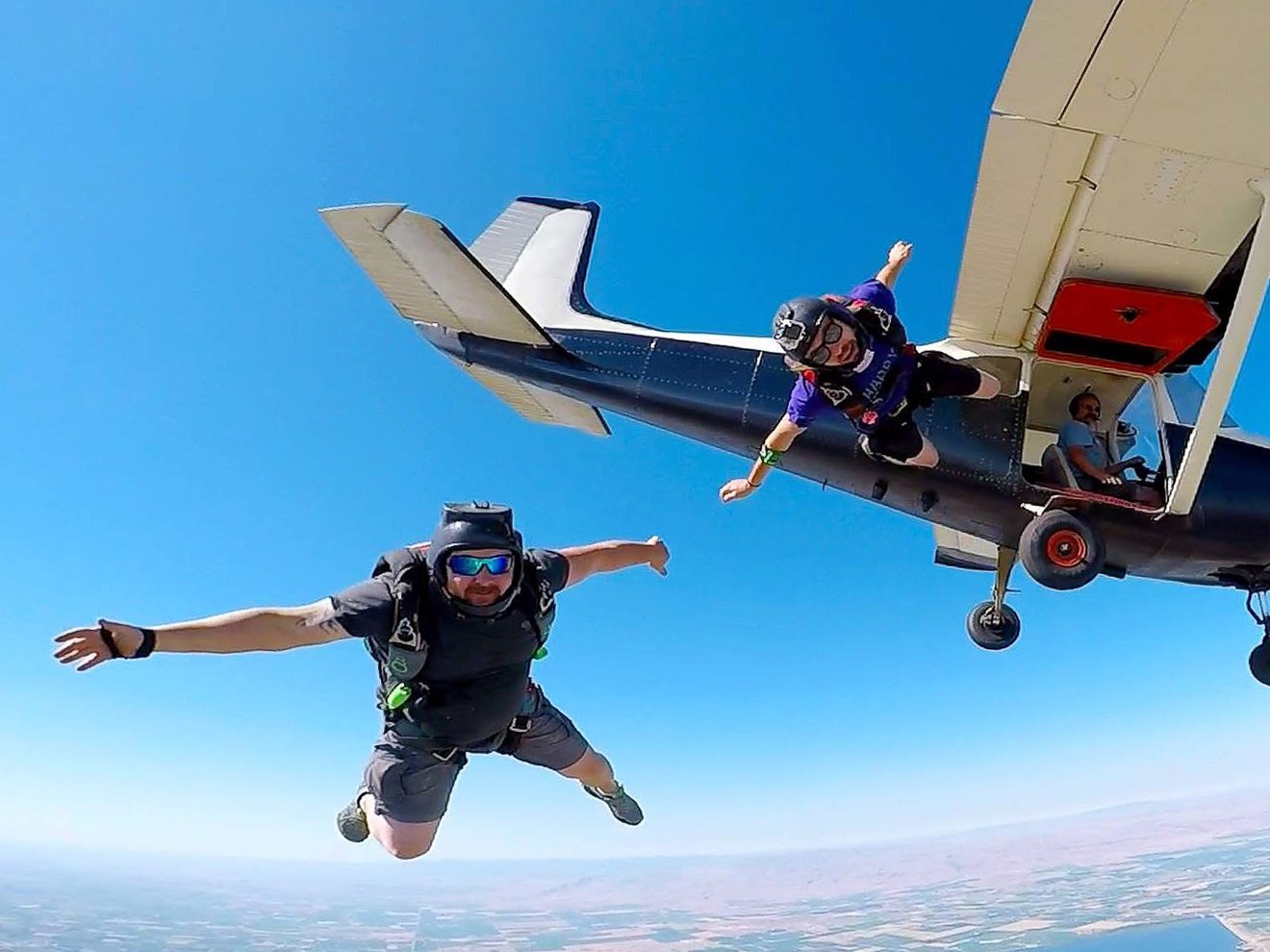 Sport jumpers Brian Singer and John Alcorn jumping out of a Cessna 182 equipped with a supercharged 550 engine during a Skydown jump, with Lake Lowell in the background.