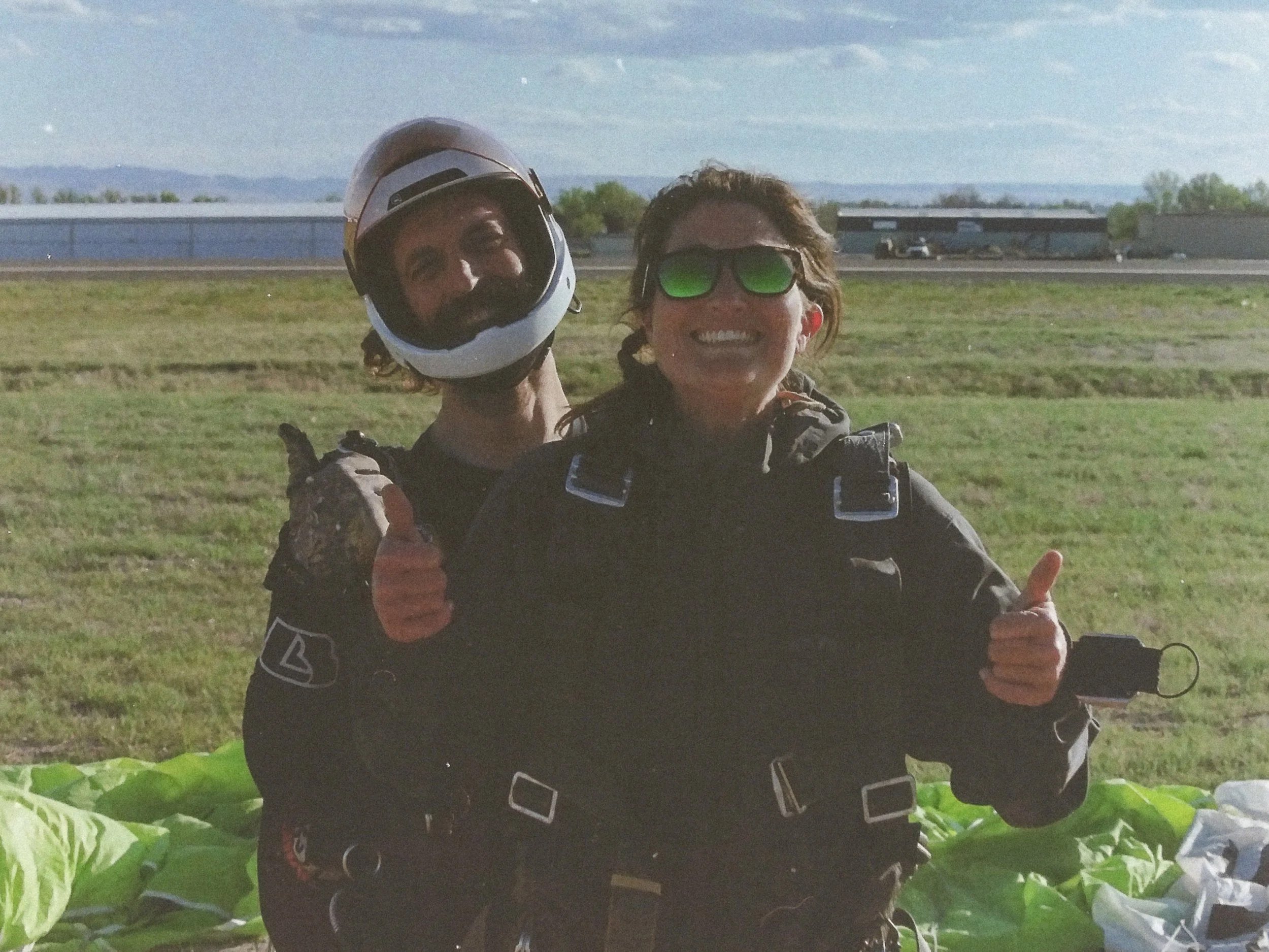 Two skydivers smiling and giving a thumbs up immediately after landing at Skydive Skydown.