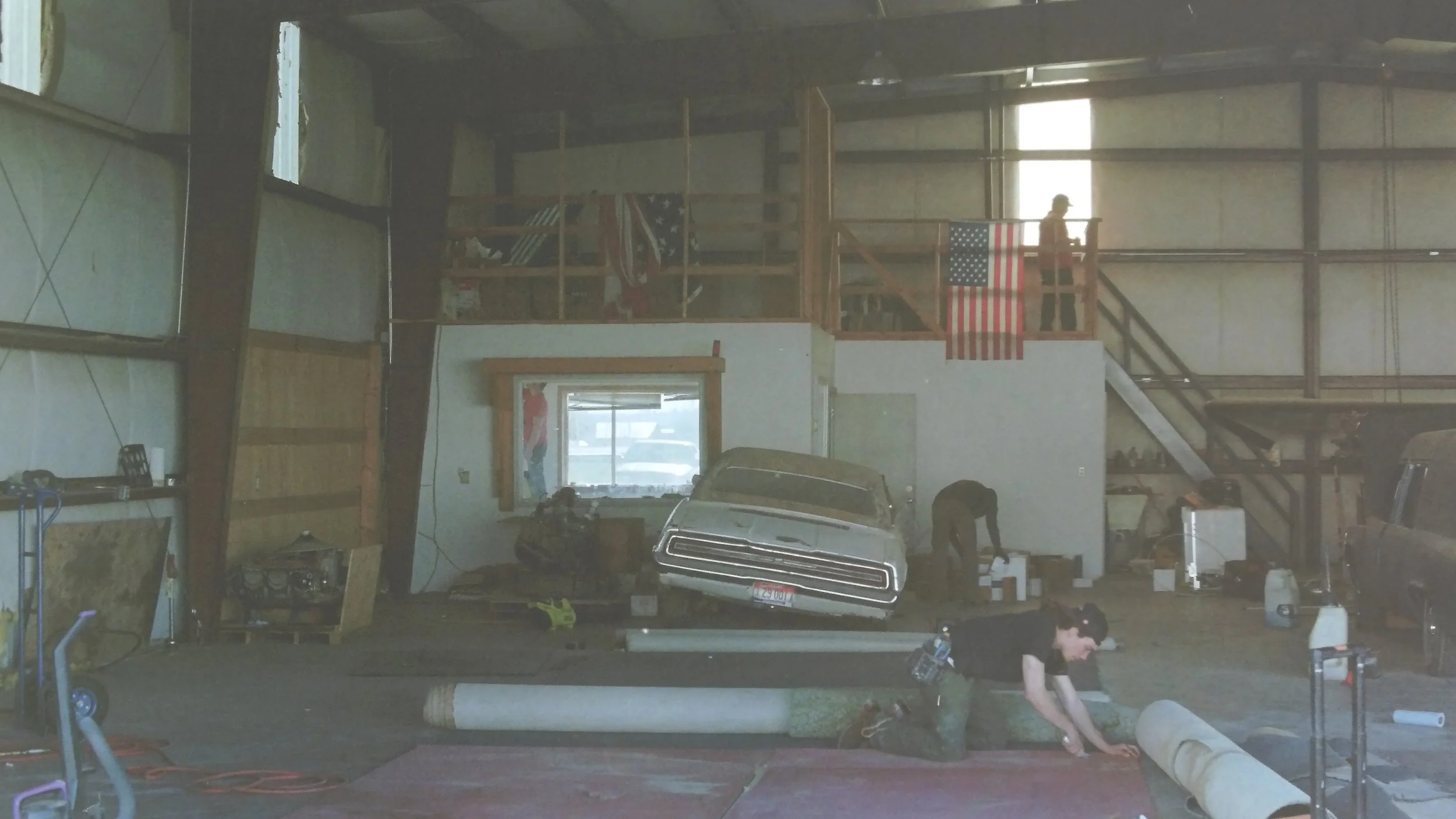 Skydive Skydown hangar before cleanup, with cars, clutter, and trash scattered throughout during the early stages of the drop zone rebuild.